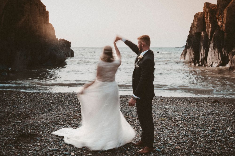 Bride twirling on secluded Ceredigion beach during West Wales coastal wedding