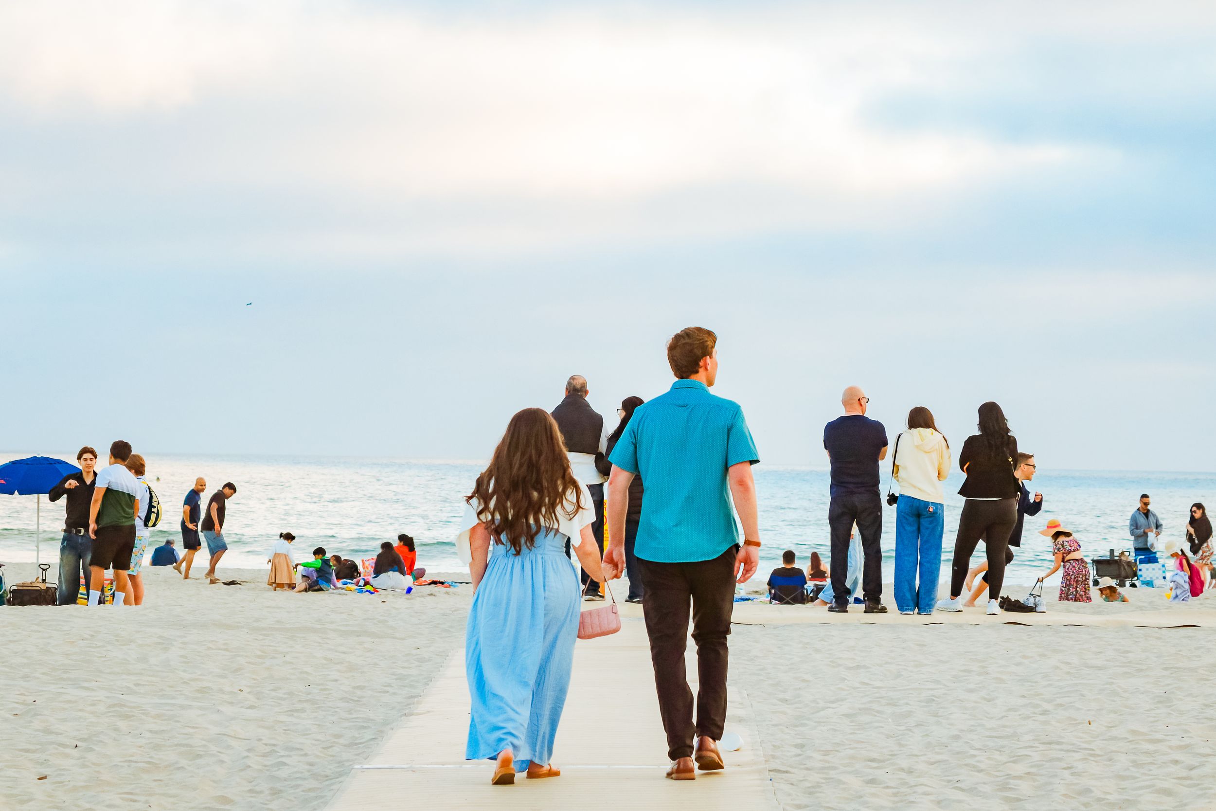 Newly engaged couple walking hand in hand along the beach at sunset by Zeus Holbrook San Diego Wedding Photographer