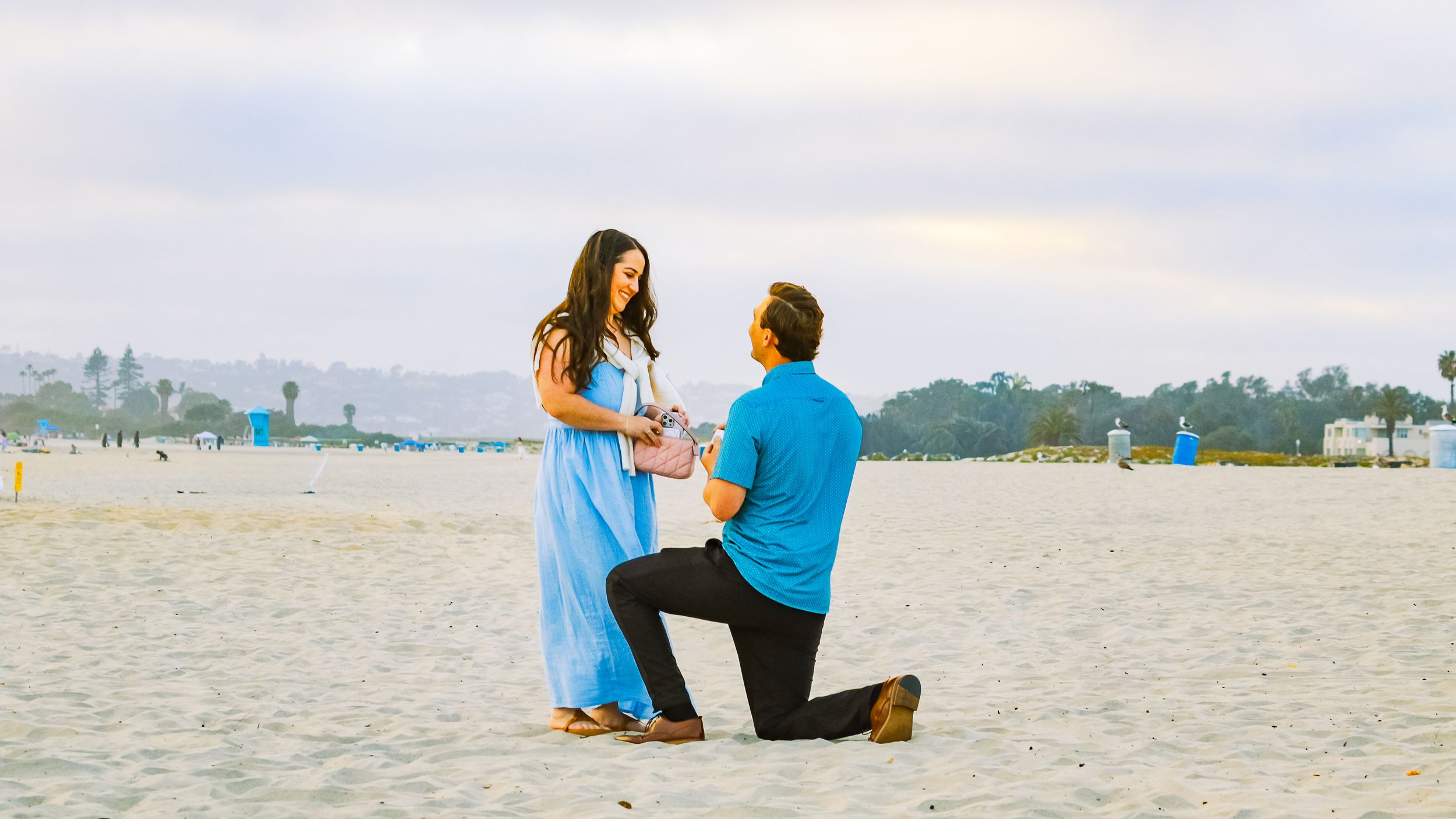 Beach proposal with man on one knee on a sandy San Diego beach captured by Zeus Holbrook San Diego Wedding Photographer