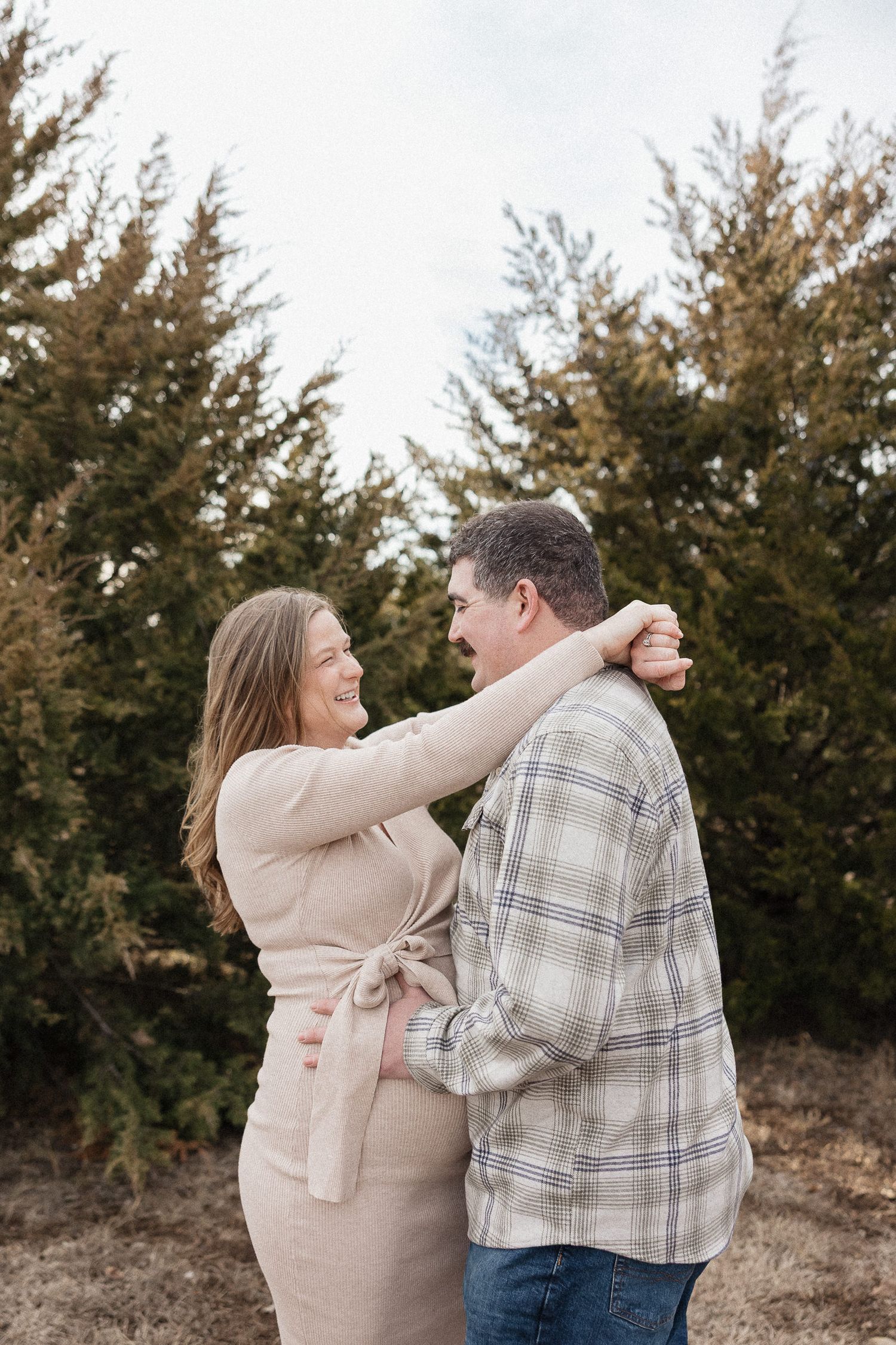 pregnant mother and dad dance together in front of lake olathe during photo session