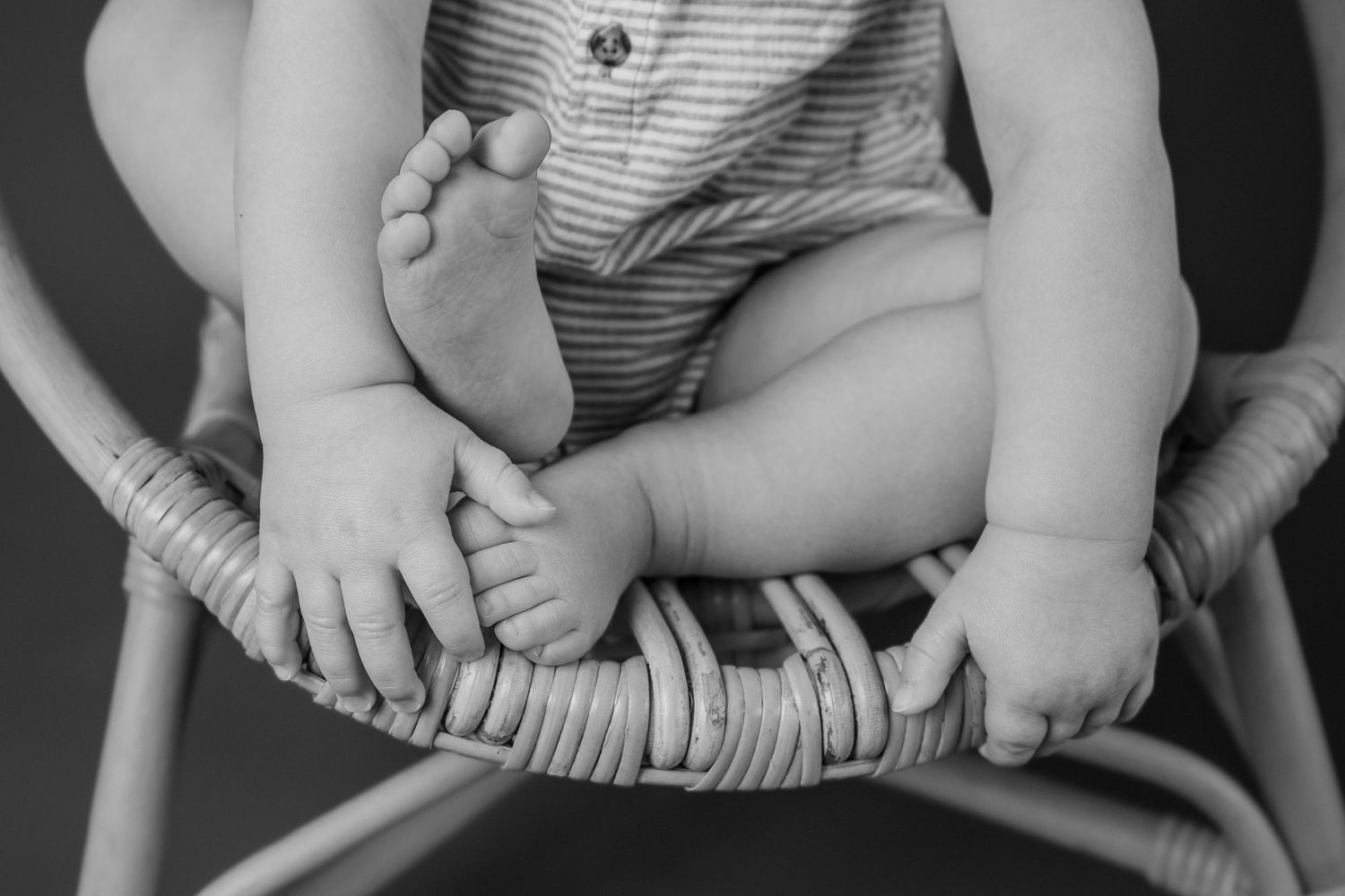 Black and white close-up detail of tiny baby feet and striped fabric.