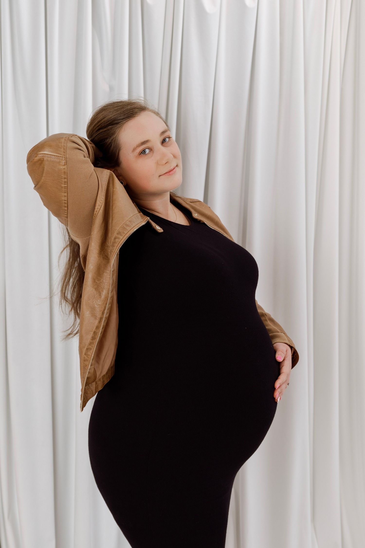 Dynamic fashion poses against white curtain backdrop in tan jacket.