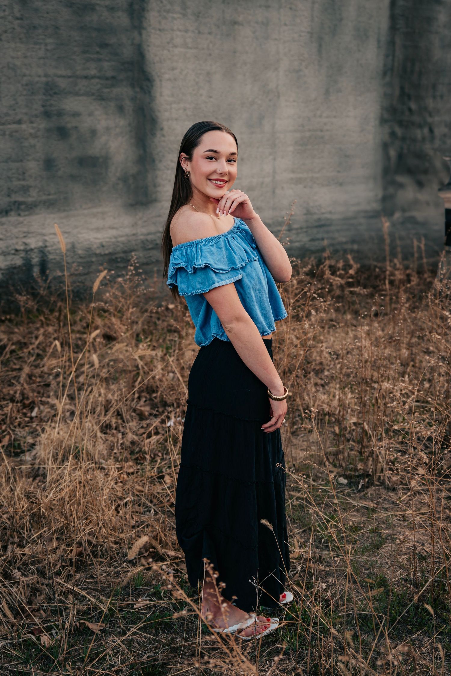Outdoor portrait series featuring a blue ruffled top and black skirt against a concrete wall.