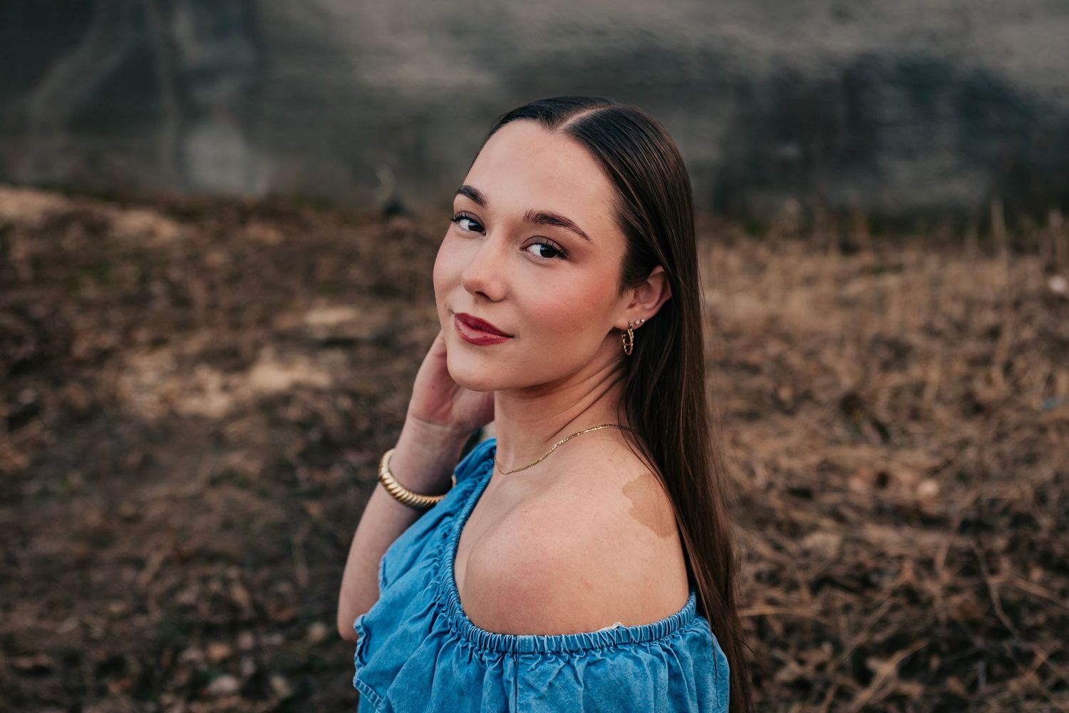 Artistic outdoor portraits with blue top against rustic backdrop at golden hour.