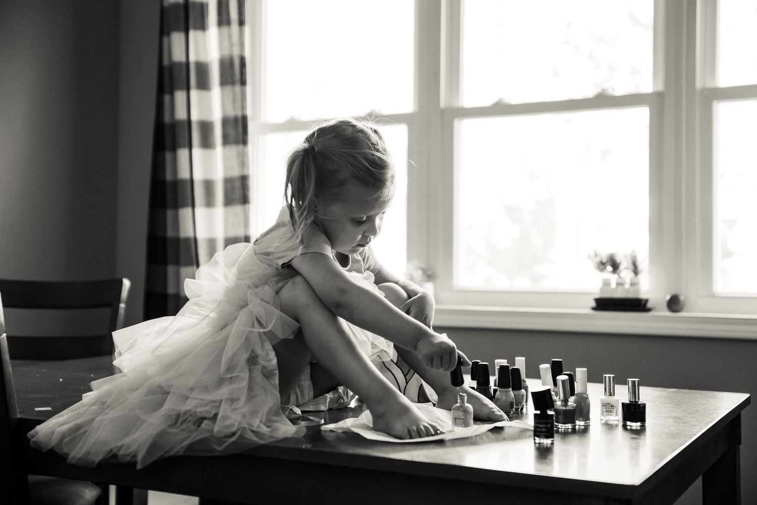 Black and white panoramic photo of bridal preparations by a bright window.