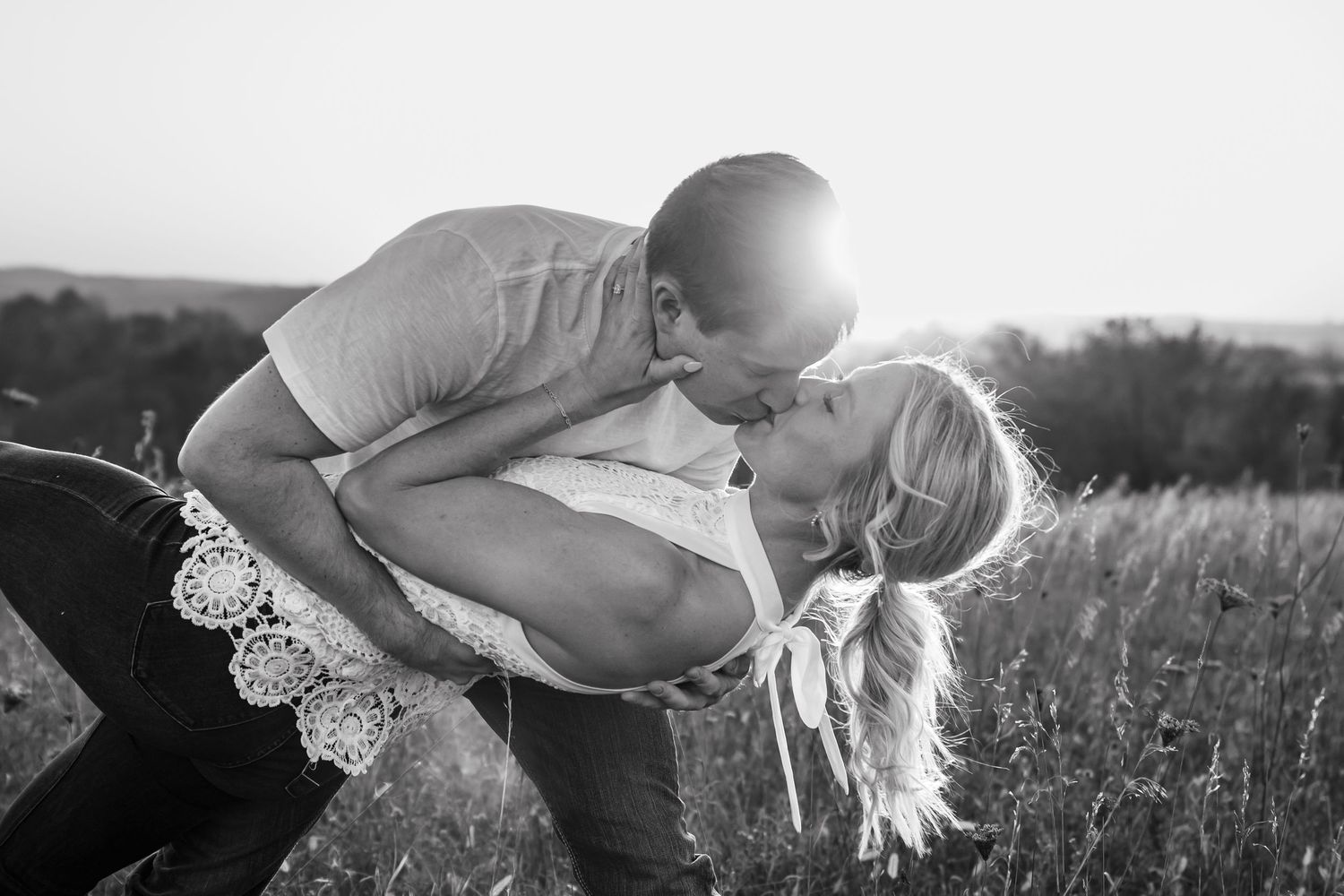 Romantic black and white portrait of couple in meadow at sunset.