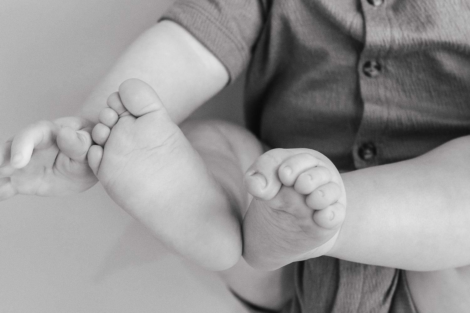 Black and white close-up of tiny newborn baby feet and toes.
