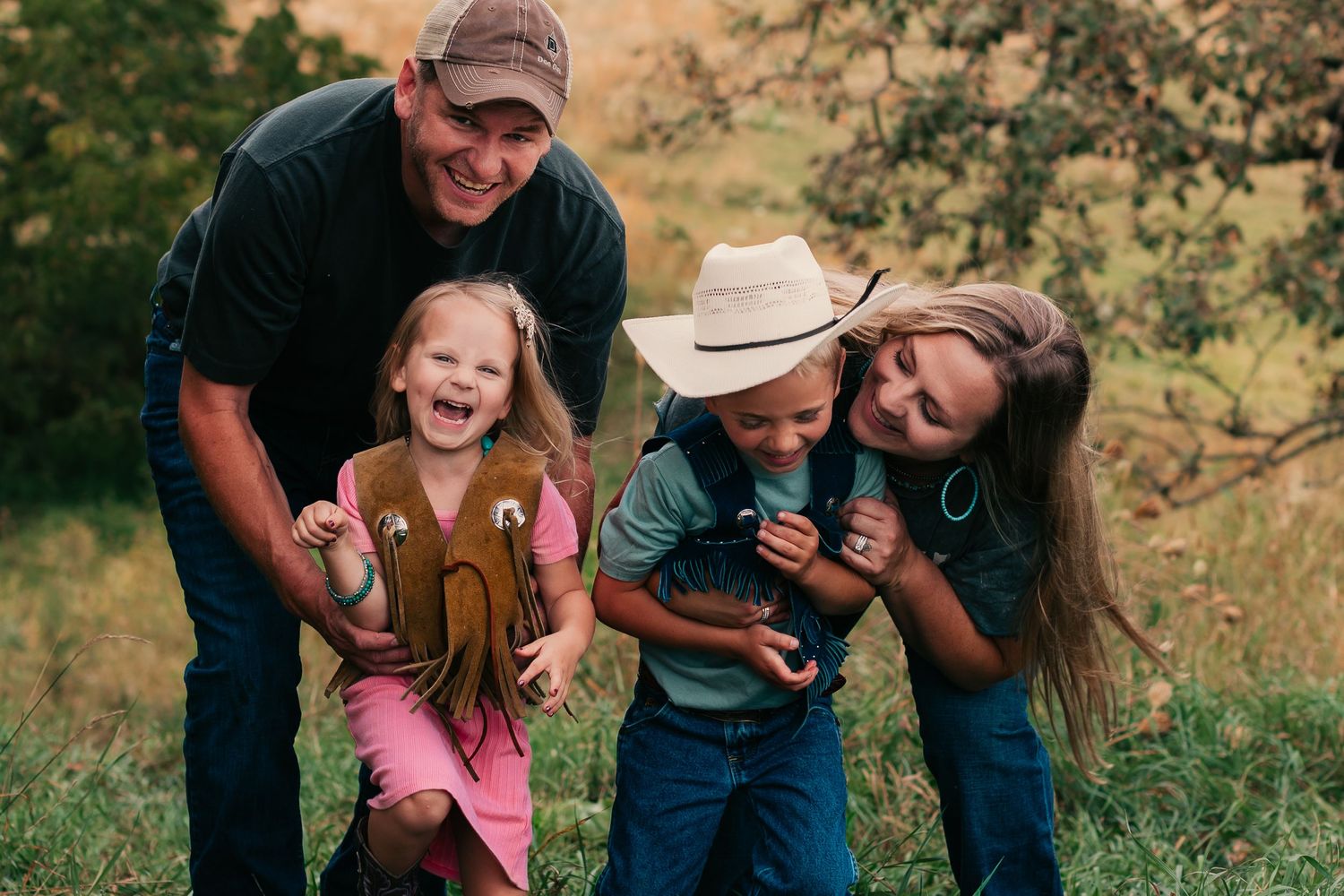 Family laughing together in a golden field during sunset photography session.