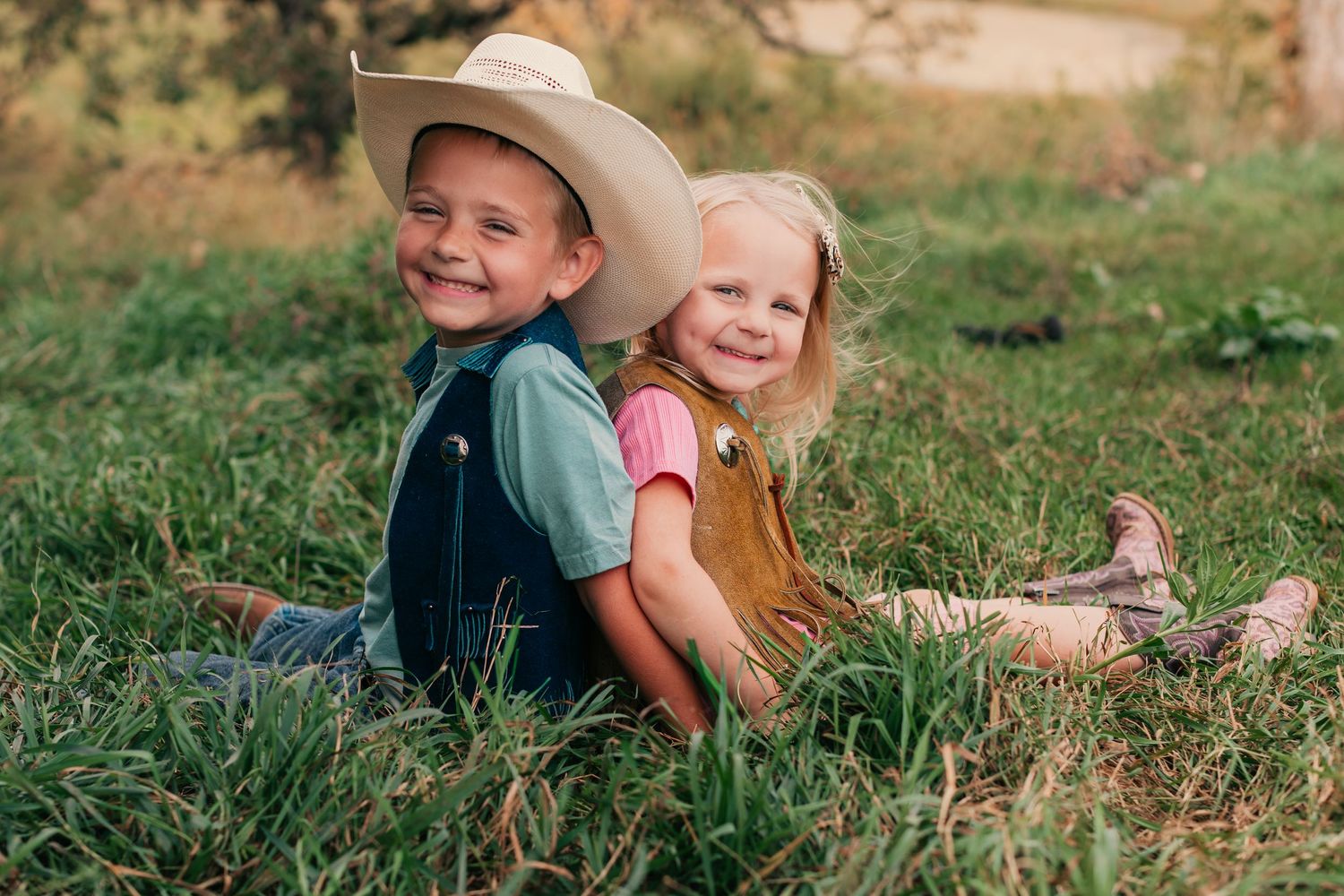 Children playing and laughing together in a grassy field wearing casual summer clothing.