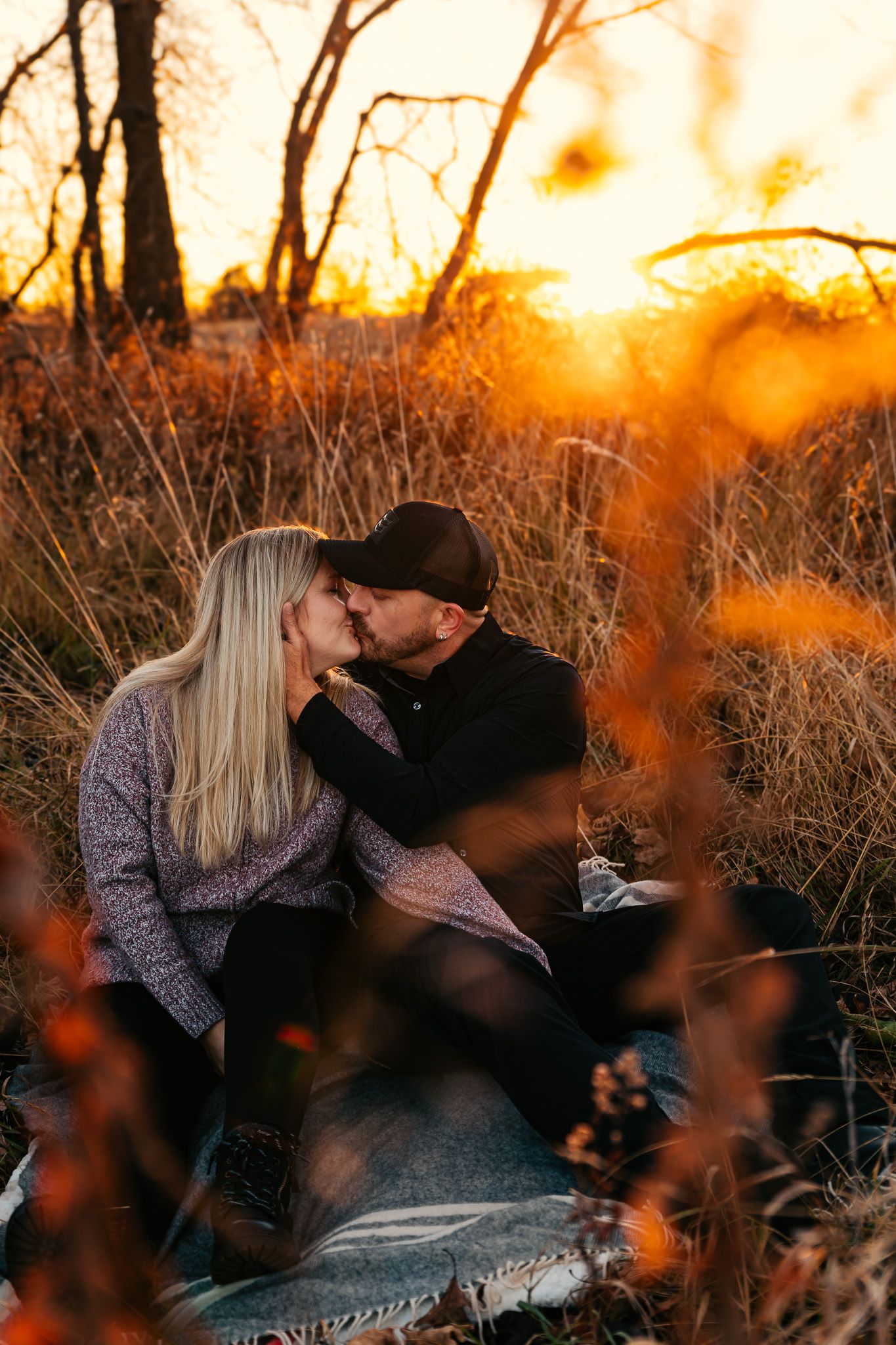Romantic couple sharing intimate moment at sunset in tall grass field.