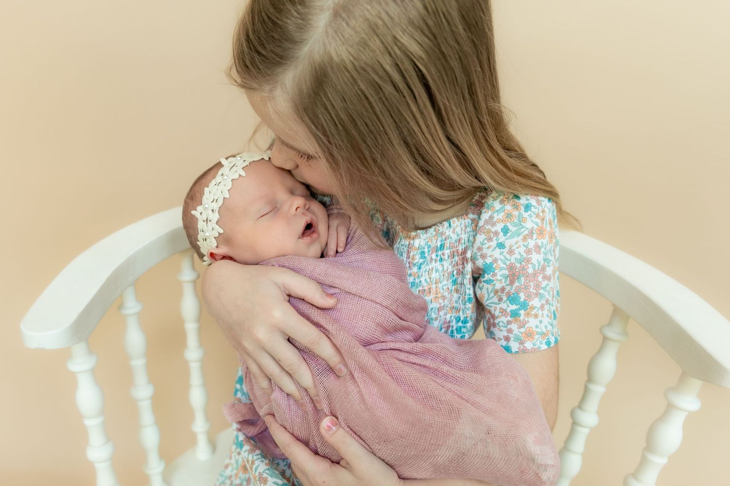 Candid indoor family portraits showing tender moments against a neutral beige background.