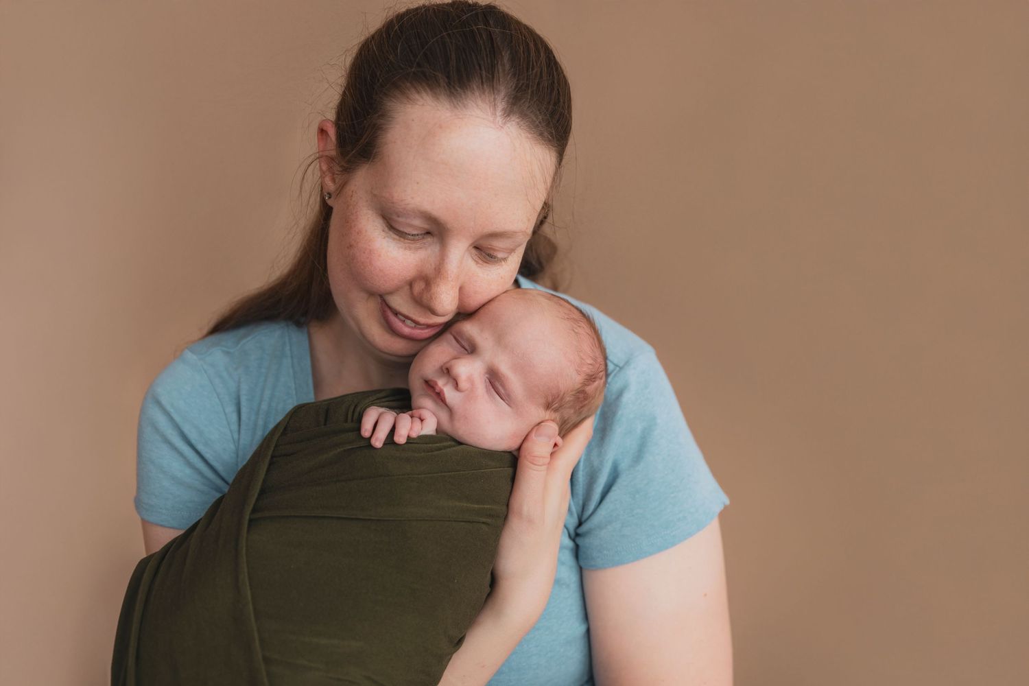 Intimate lifestyle portrait session against neutral brown backdrop.