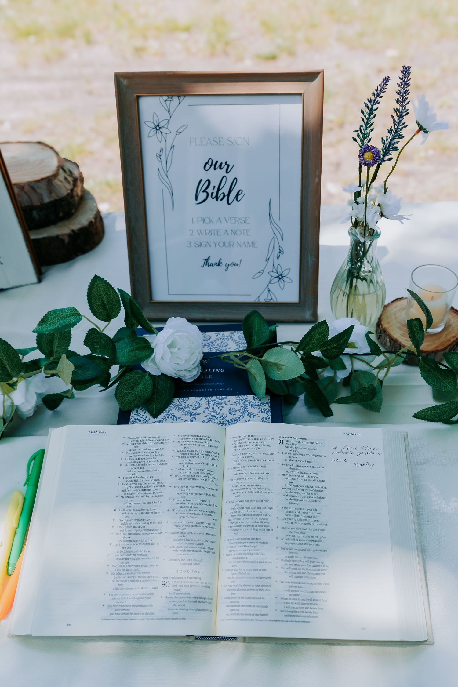 Open Bible with decorative frame and floral arrangements on white surface.