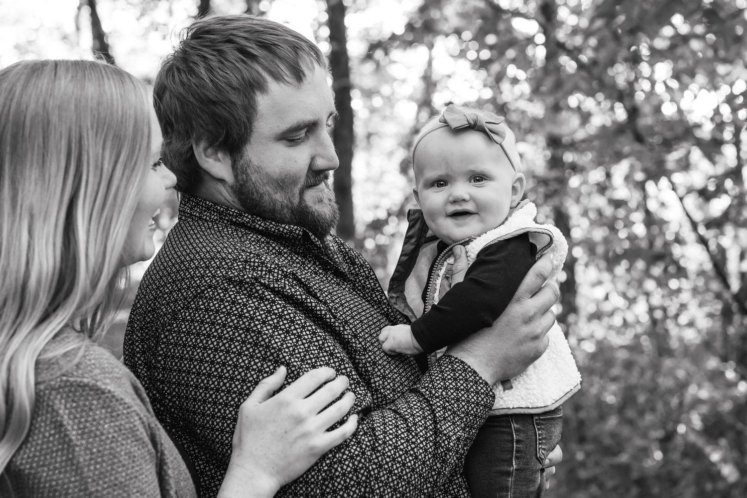 Family moment captured in black and white among trees.