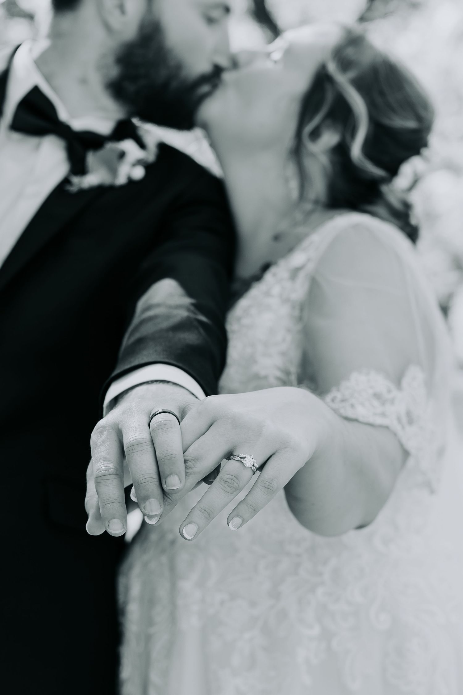 Black and white close-up of newlyweds' hands showing wedding rings.
