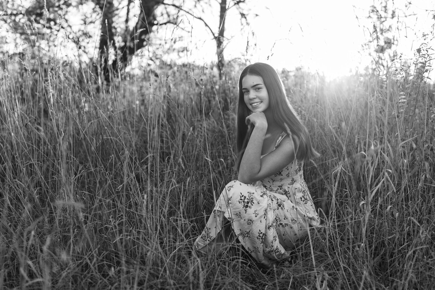 Black and white portrait session in tall grass field at sunset.