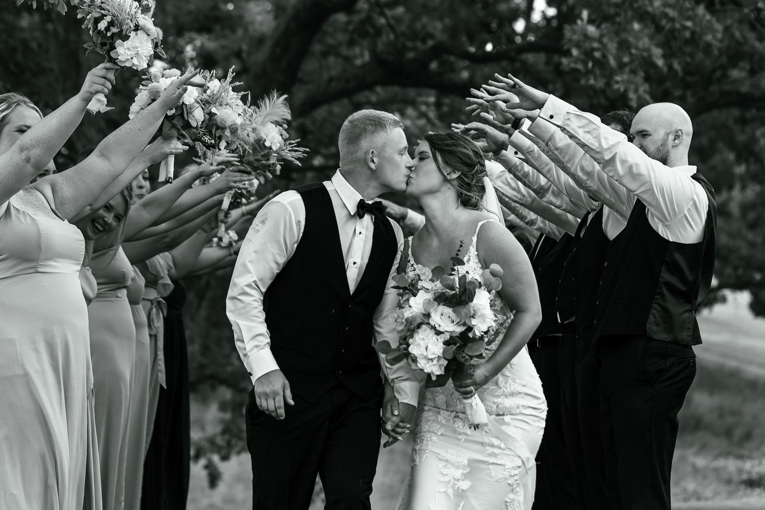 Wedding party celebrating with arms raised in black and white photography.