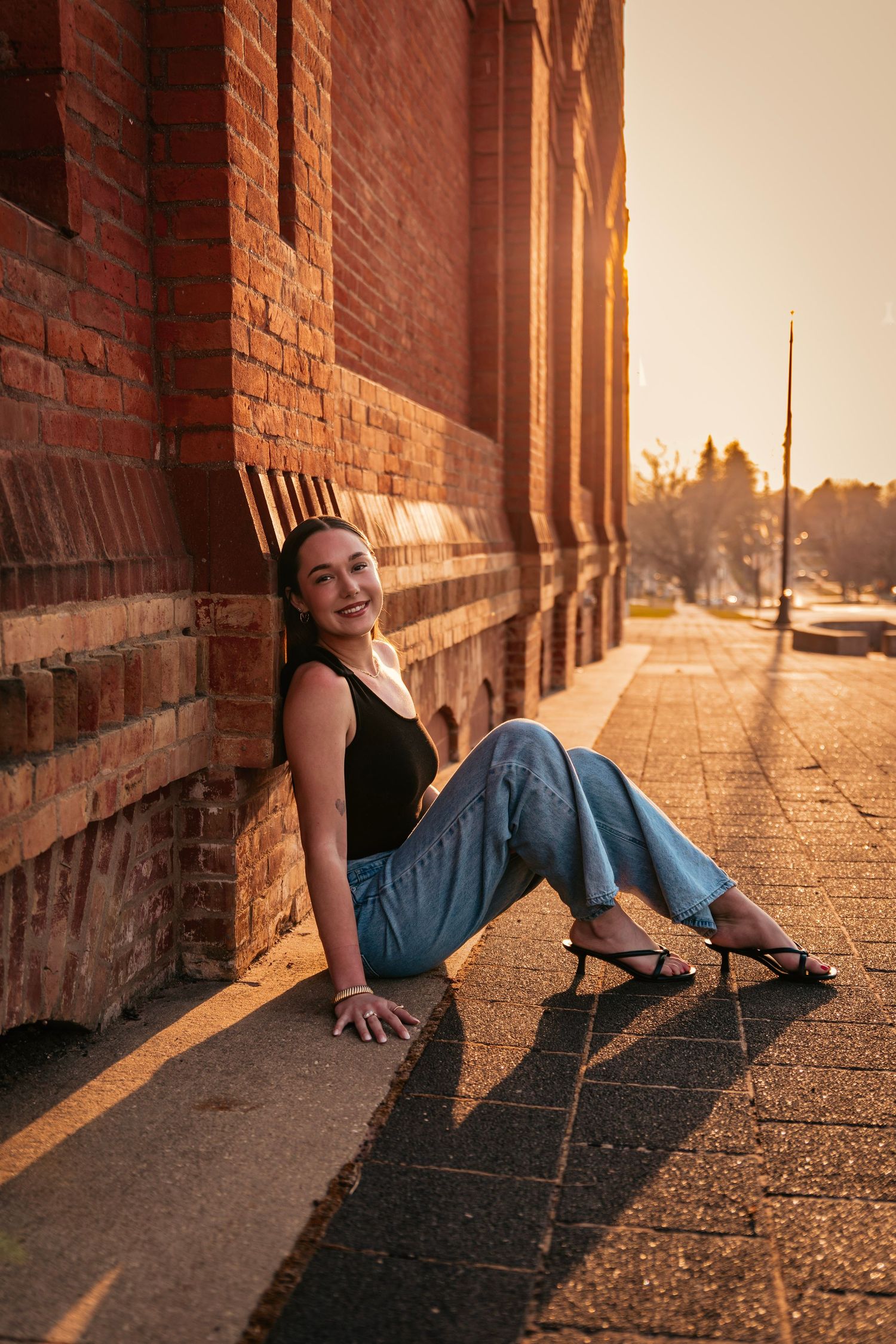 Sunset portrait session against brick wall with dramatic golden hour lighting.