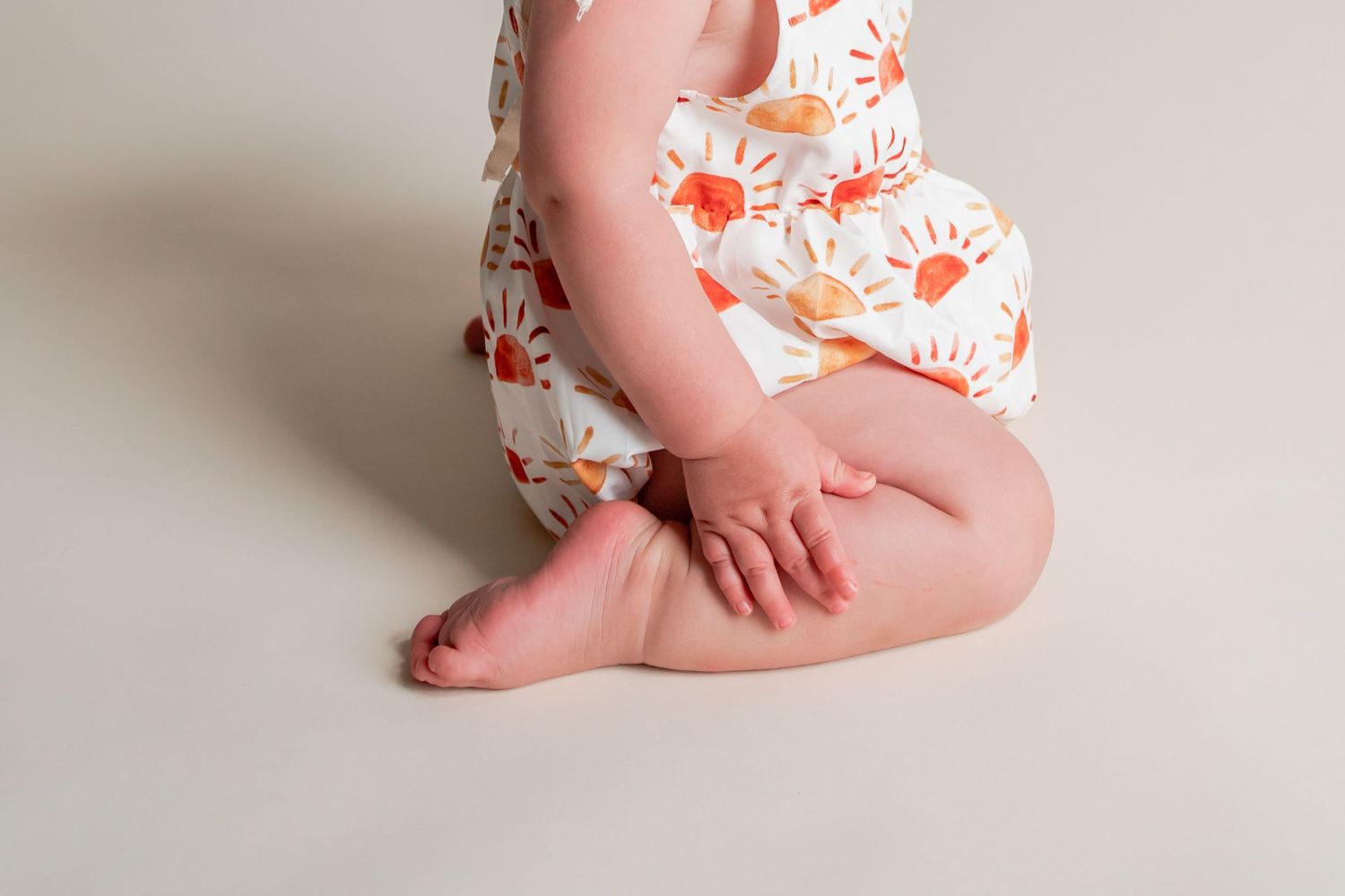Baby wearing floral outfit during professional photo session against neutral background.