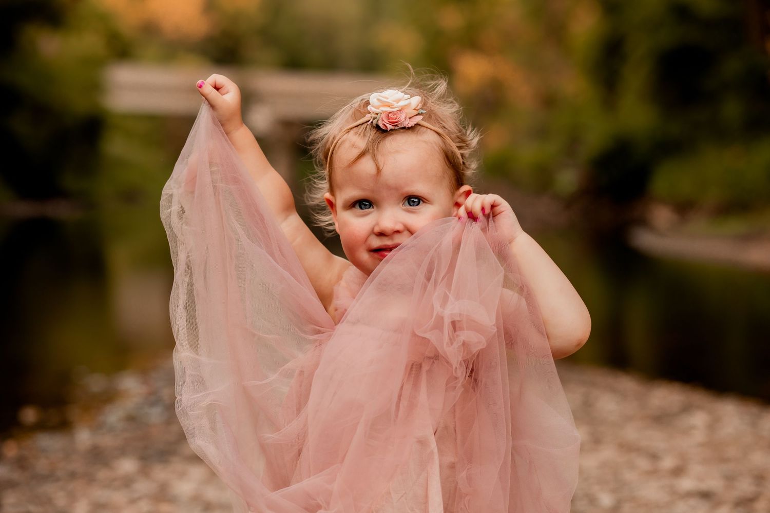Young child twirling in flowing pink tulle dress among autumn leaves.