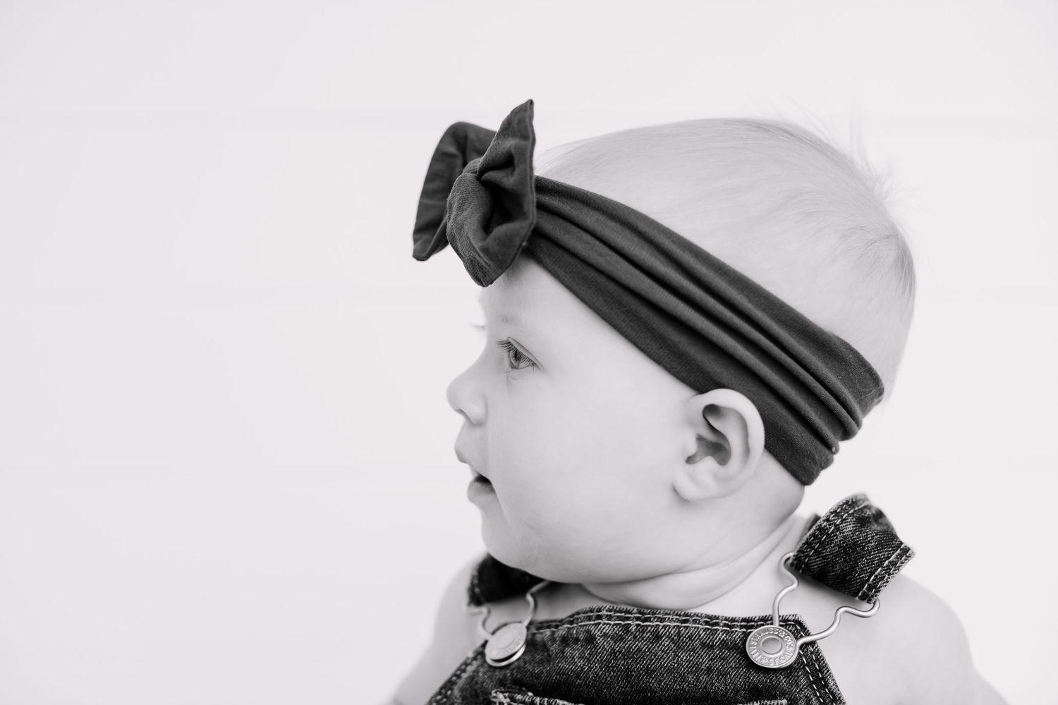 Side profile of baby wearing striped headband in black and white photography.