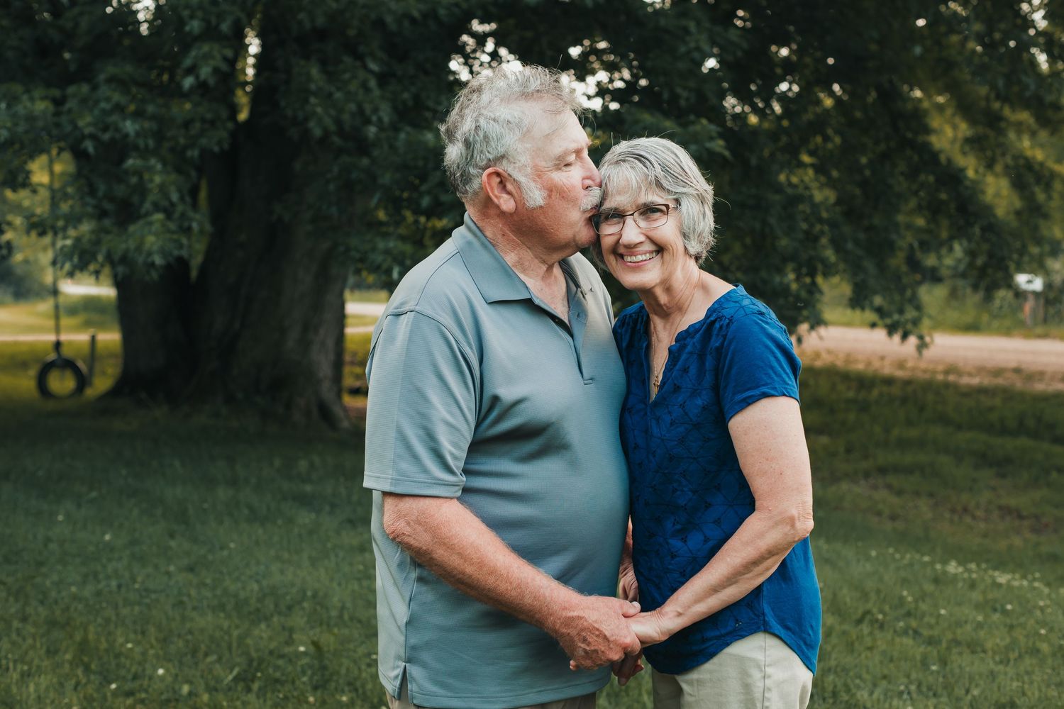 Elderly couple sharing tender moments together in a sunny outdoor garden setting.