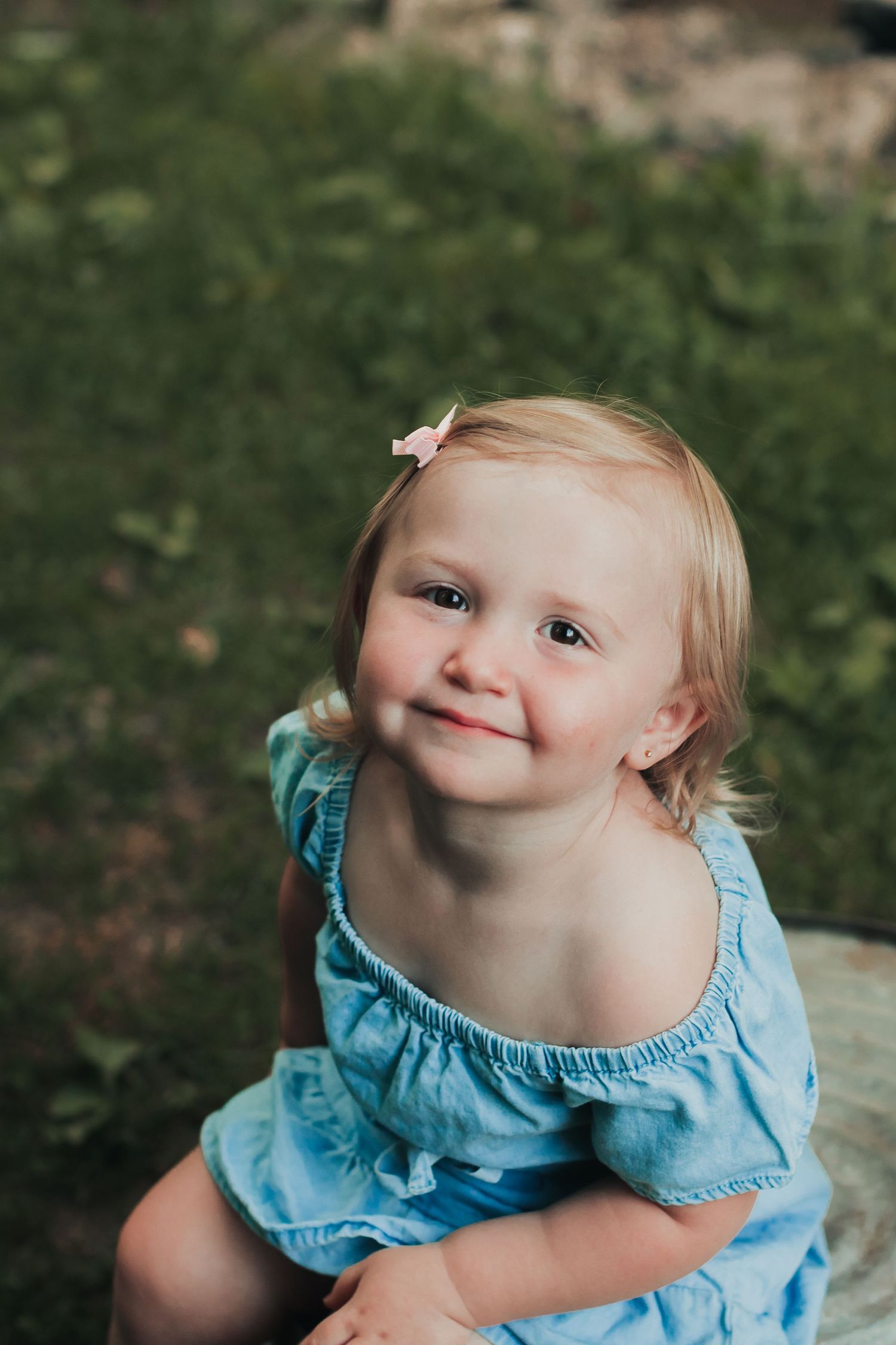 Adorable baby in light blue ruffled dress smiling and playing outdoors.
