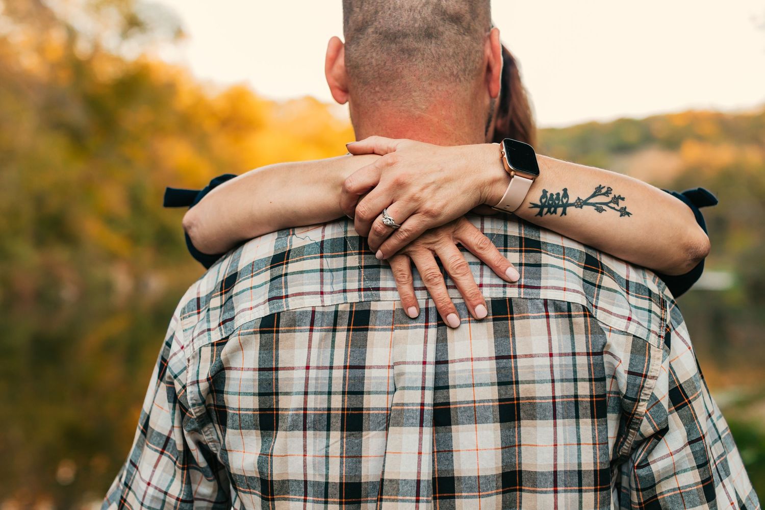 Close-up shot of hands holding each other against a plaid shirt background.