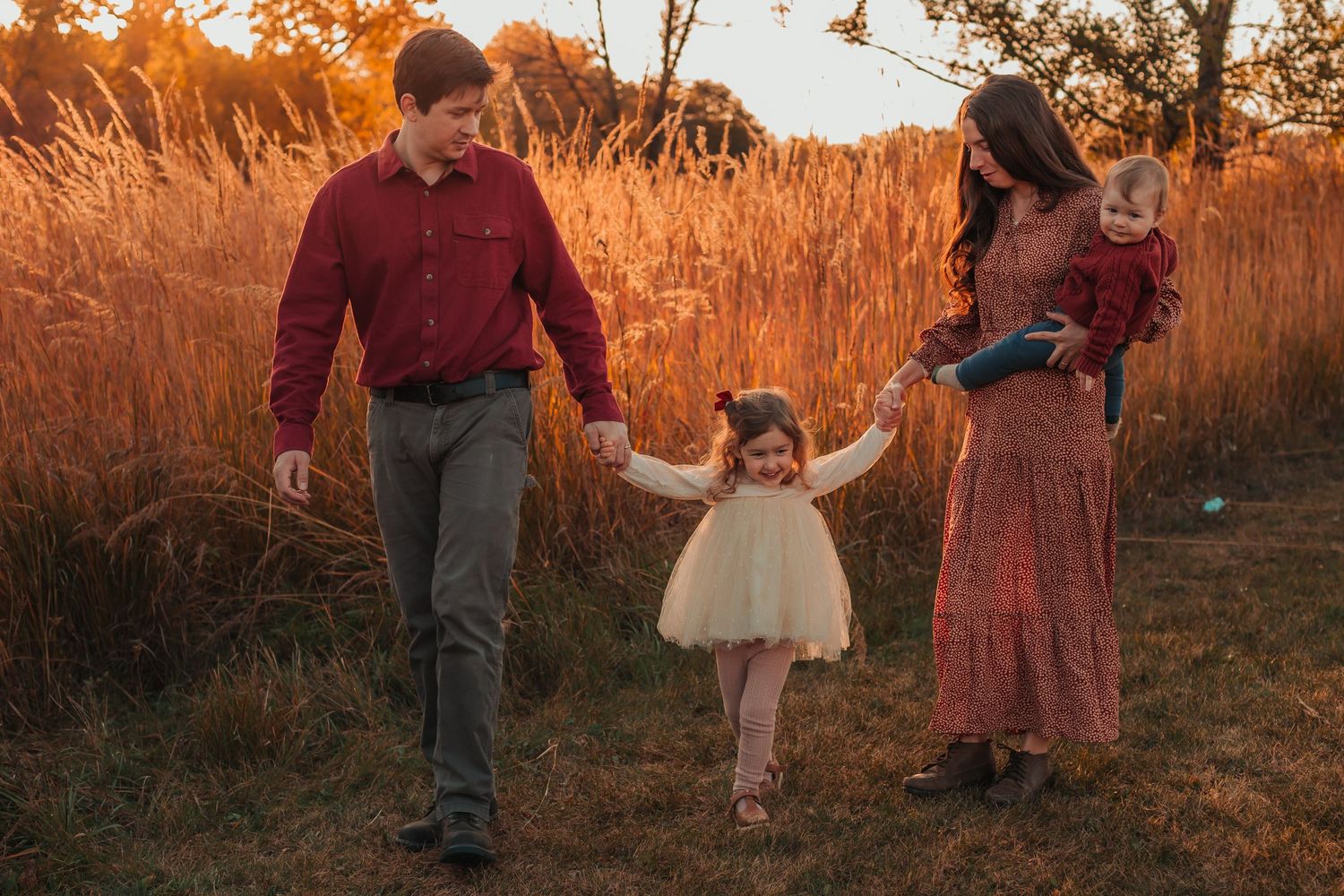 Family portraits at golden hour with tall orange grasses in background.
