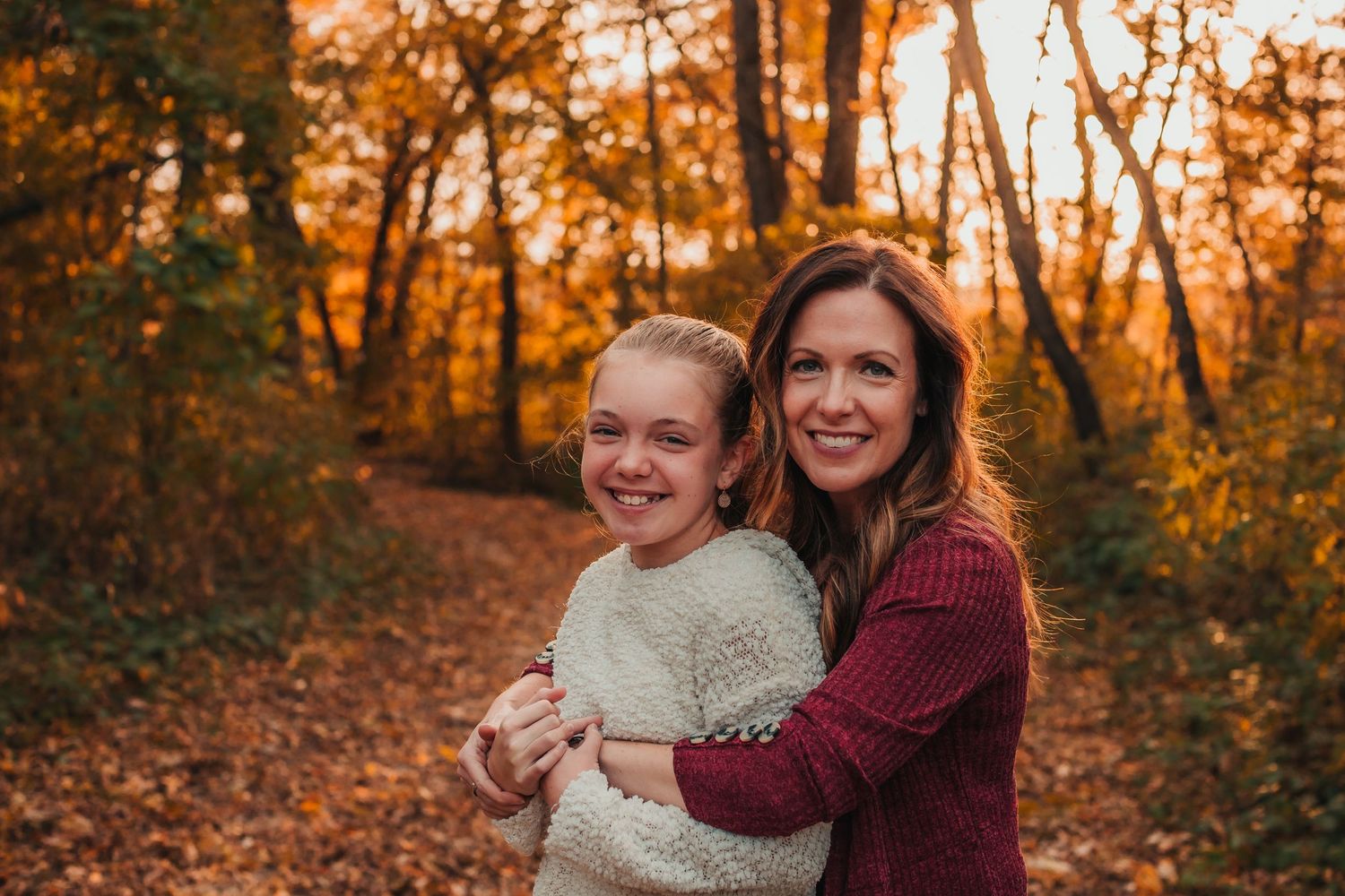 Family portraits captured in a vibrant autumn forest setting during golden hour sunset.