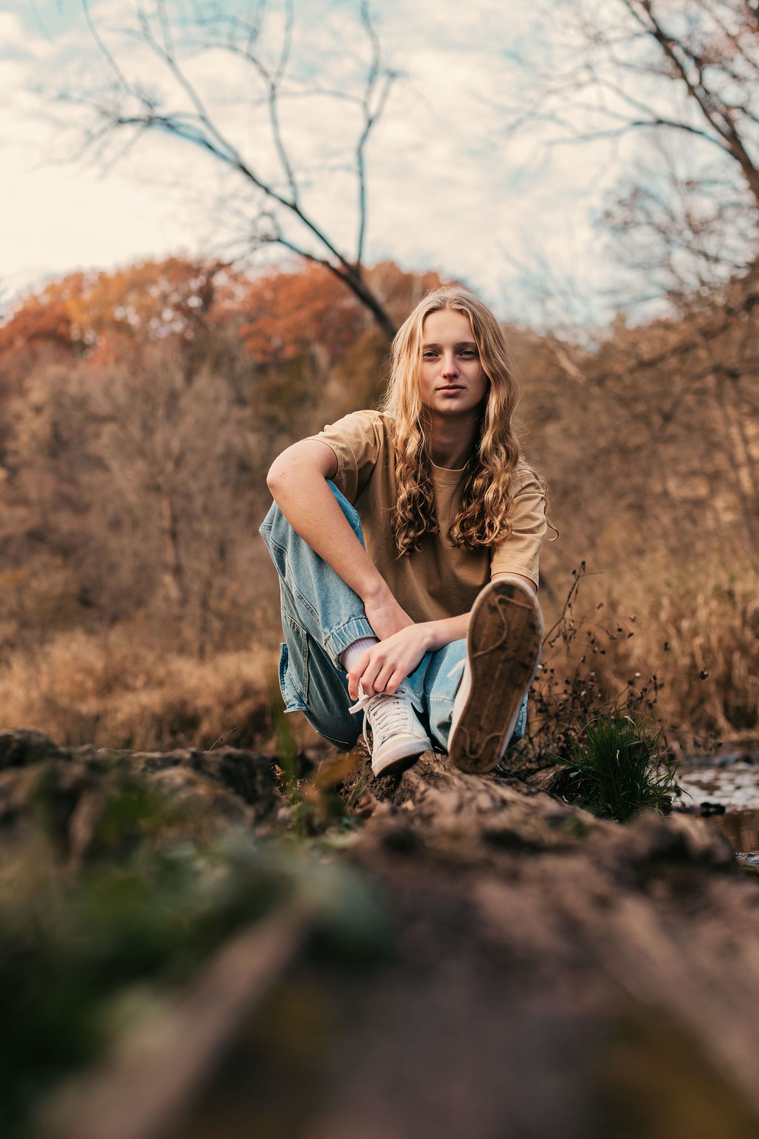 A casual autumn portrait of someone sitting on rocks in warm fall colors.