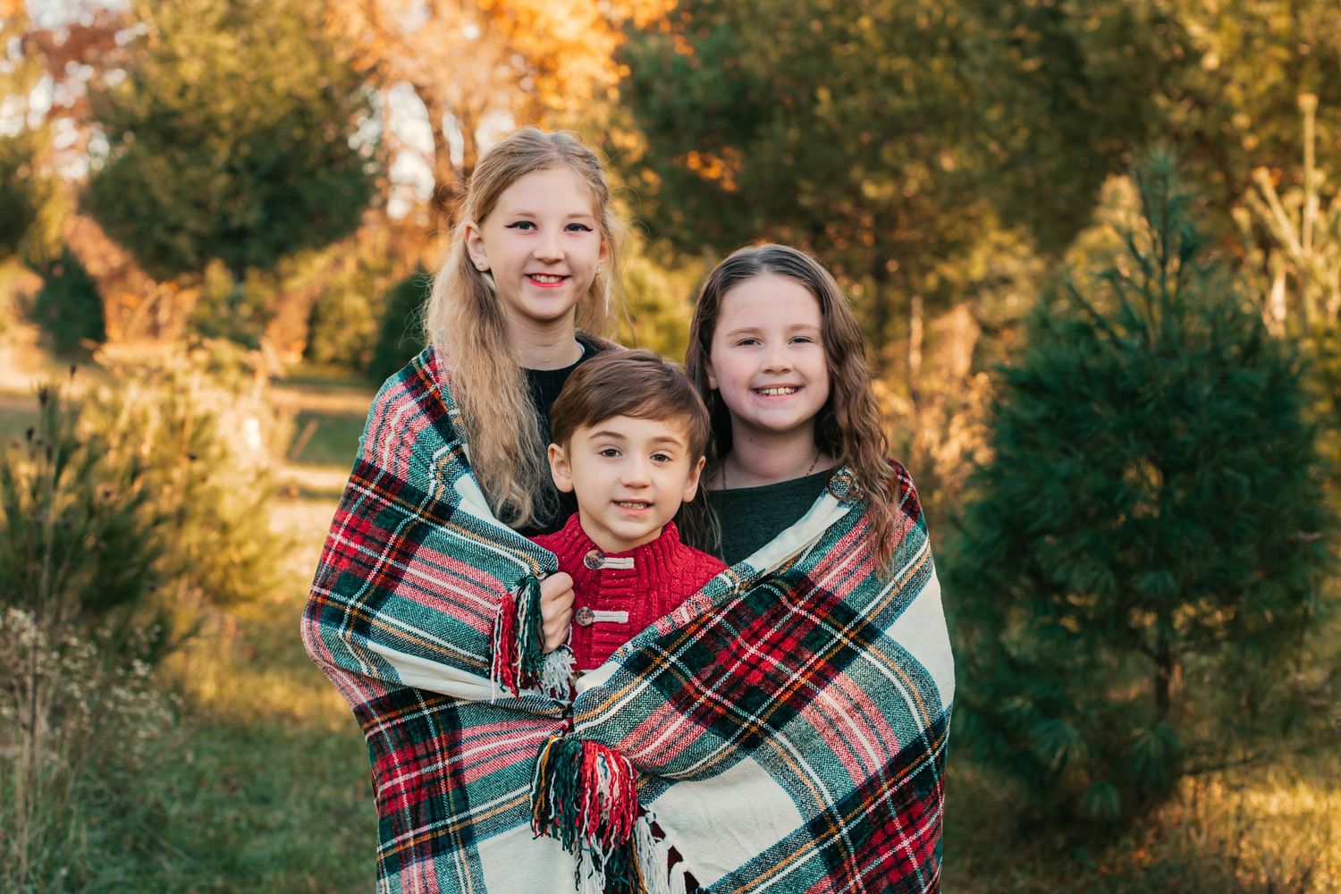 Family group wrapped in plaid blankets during autumn outdoor photo session.