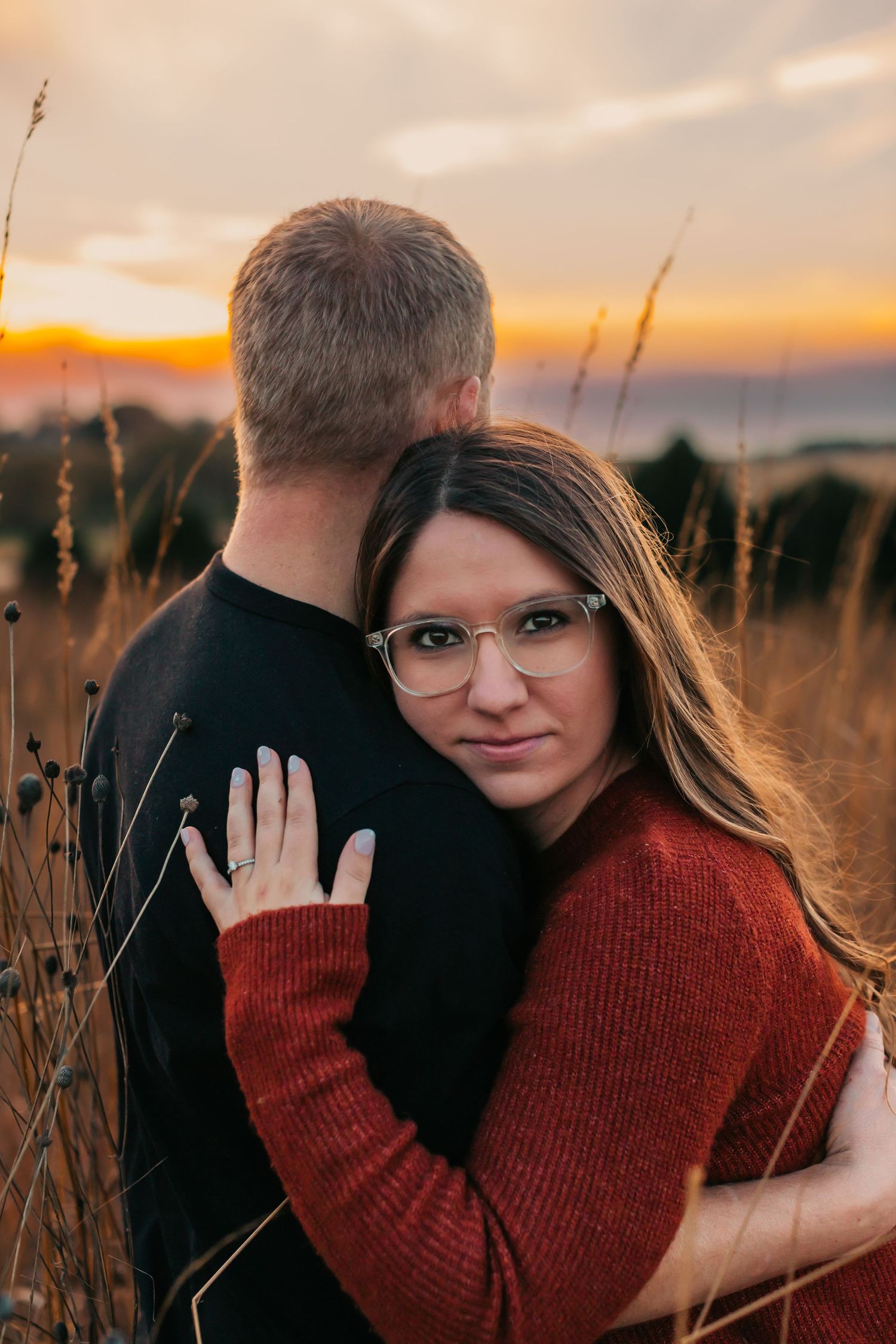 Romantic couple portraits in a field at sunset with warm autumn tones.
