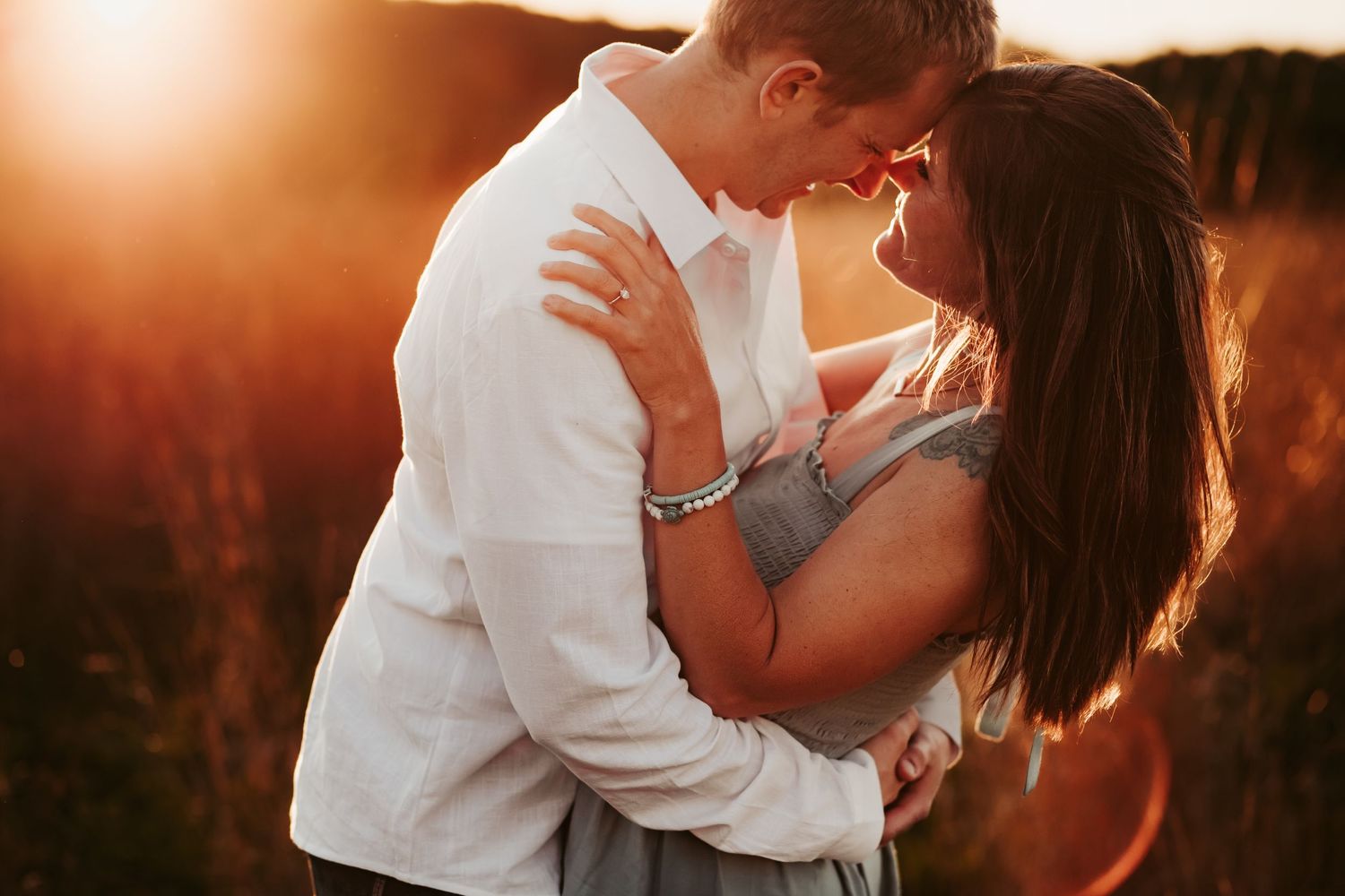 A couple embraces in a romantic pose during golden hour sunset.