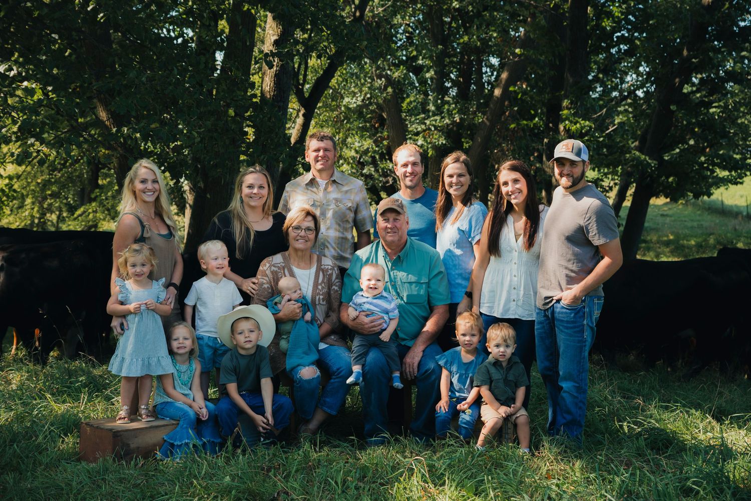 Large family group poses together outdoors in coordinated blue and white outfits on a sunny day.