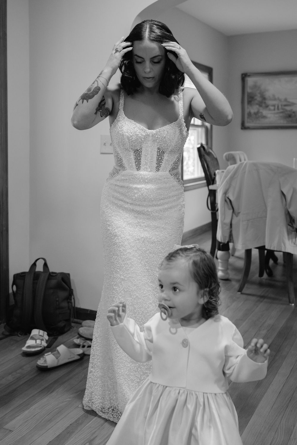 A sequence of black and white photos showing a bride getting ready with a young flower girl in matching white dresses.