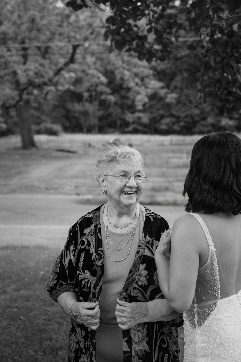 Two people share a joyful laugh together while sitting outdoors in a park setting.