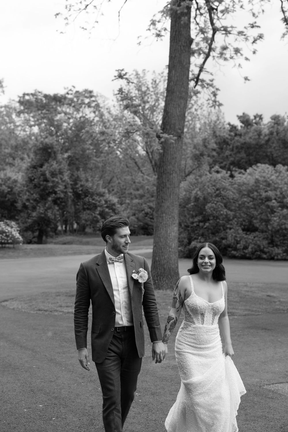Black and white photo sequence shows a couple in wedding attire walking and smiling together in a park setting.