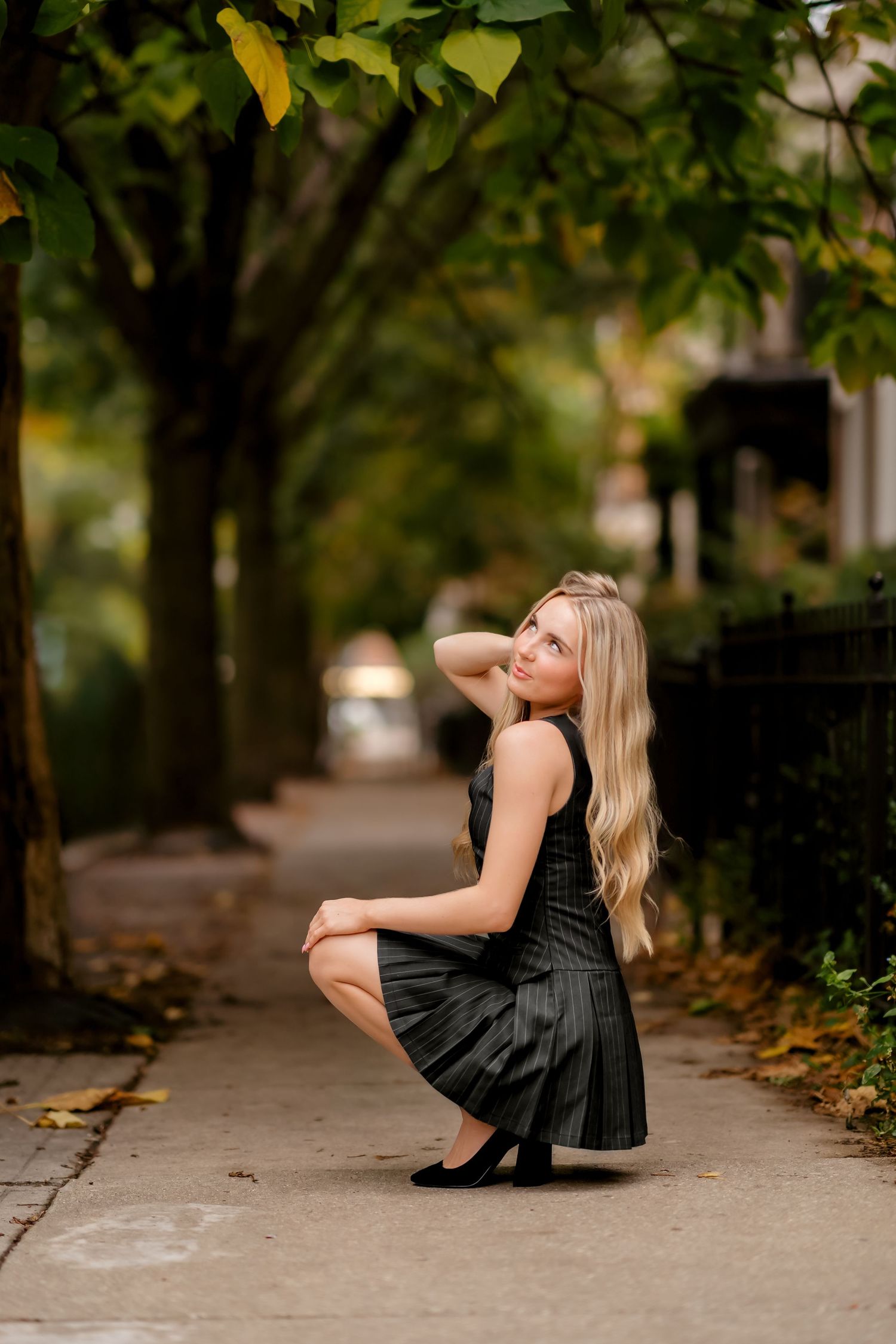 A sequence of artistic poses on a sidewalk with fall leaves and trees in the background.
