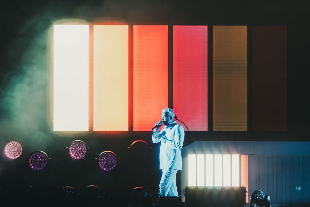 A concert stage illuminated with colorful lights and fog effects creates a dramatic performance atmosphere.