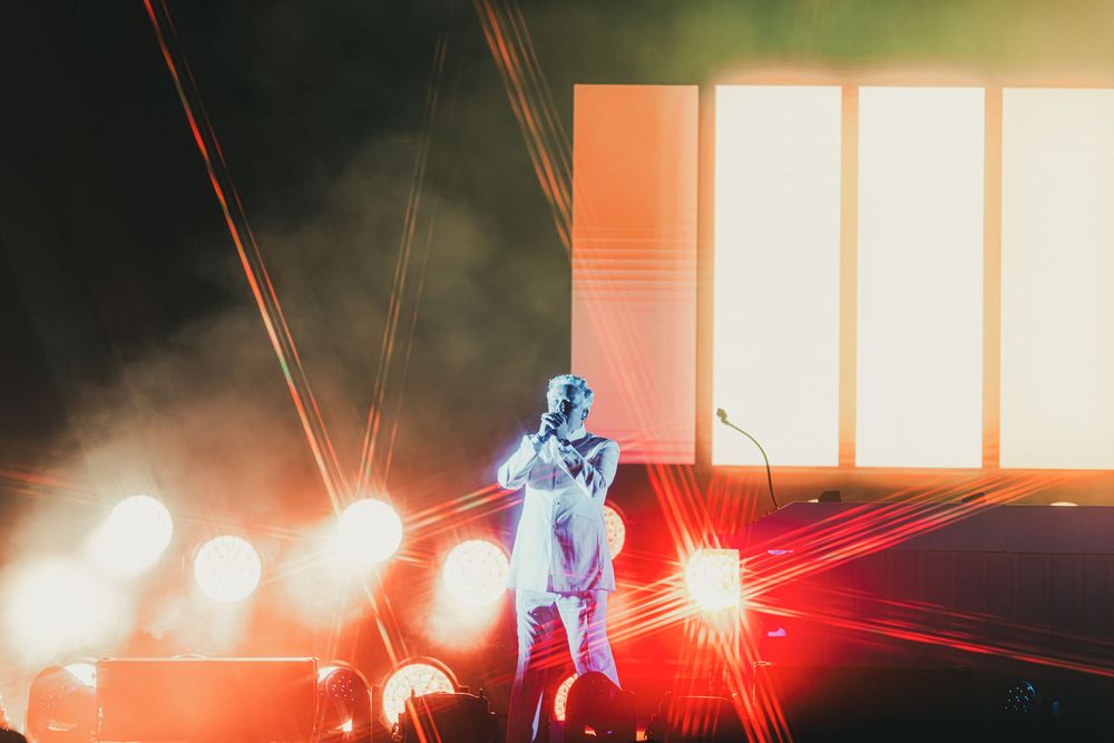 Dramatic concert stage performance with red laser beams cutting through atmospheric fog effects.