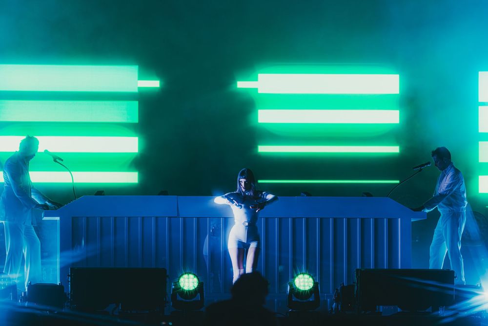 Bright turquoise neon lights illuminate a dark room with glowing horizontal lines across multiple panels.