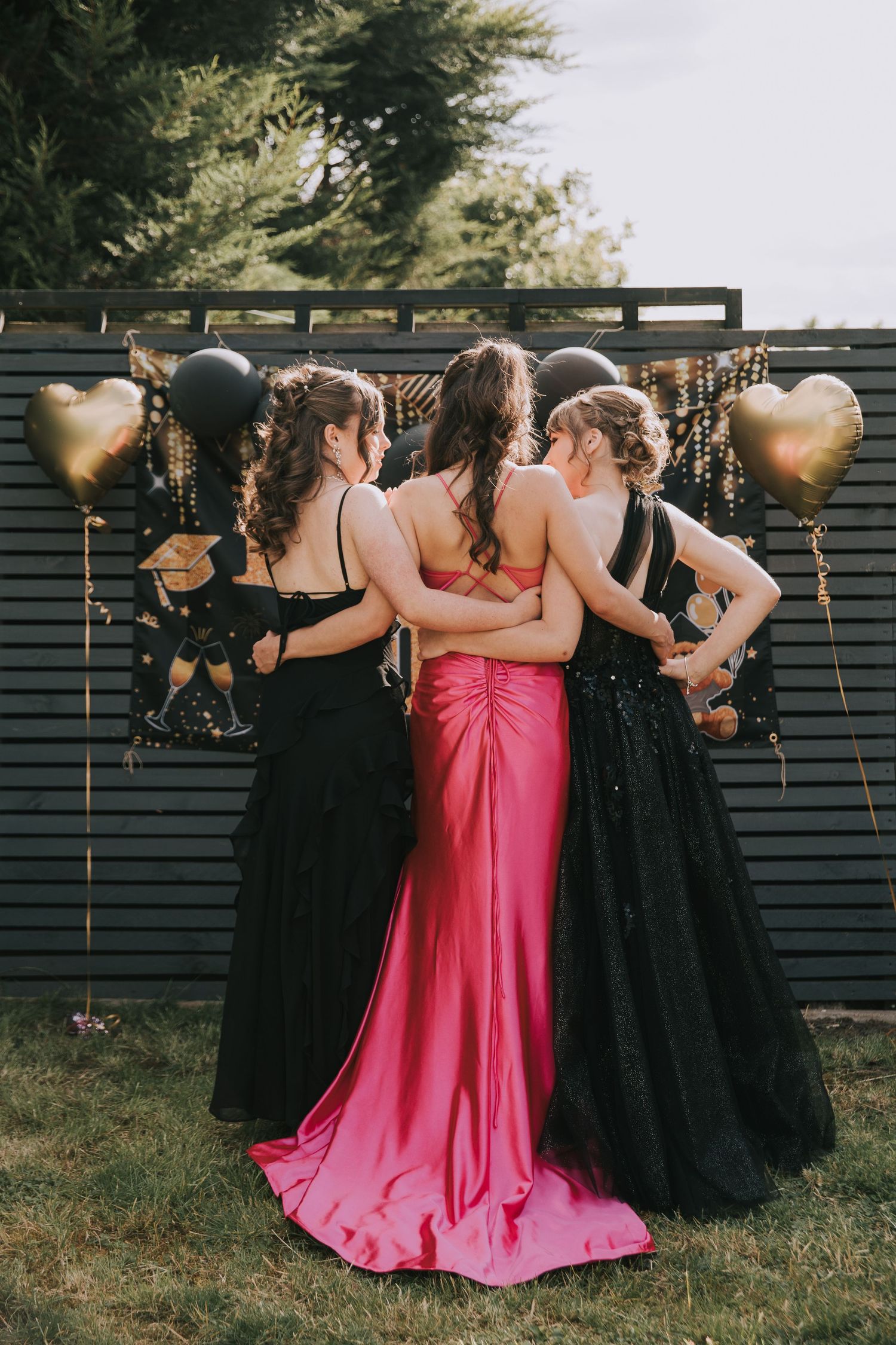 A group of bridesmaids in black dresses and one in pink pose together for a fun photo sequence outdoors.