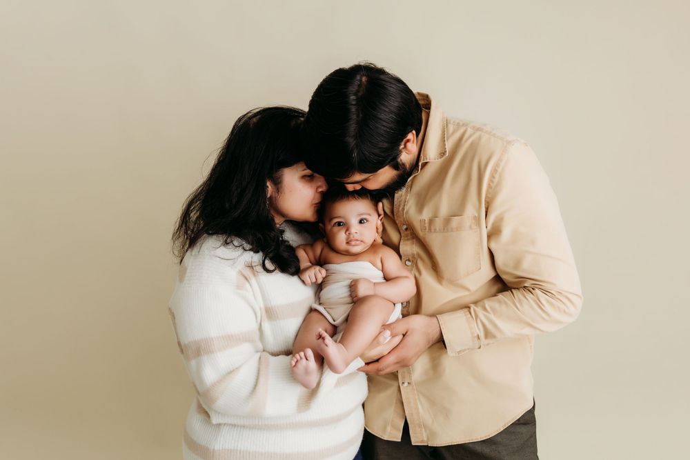 A series of intimate black and white photos showing tender moments between parent and child in a studio setting.