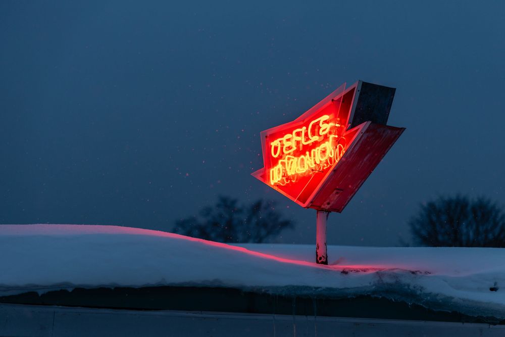 Red neon signs glow against a dark blue twilight sky creating a moody urban atmosphere.