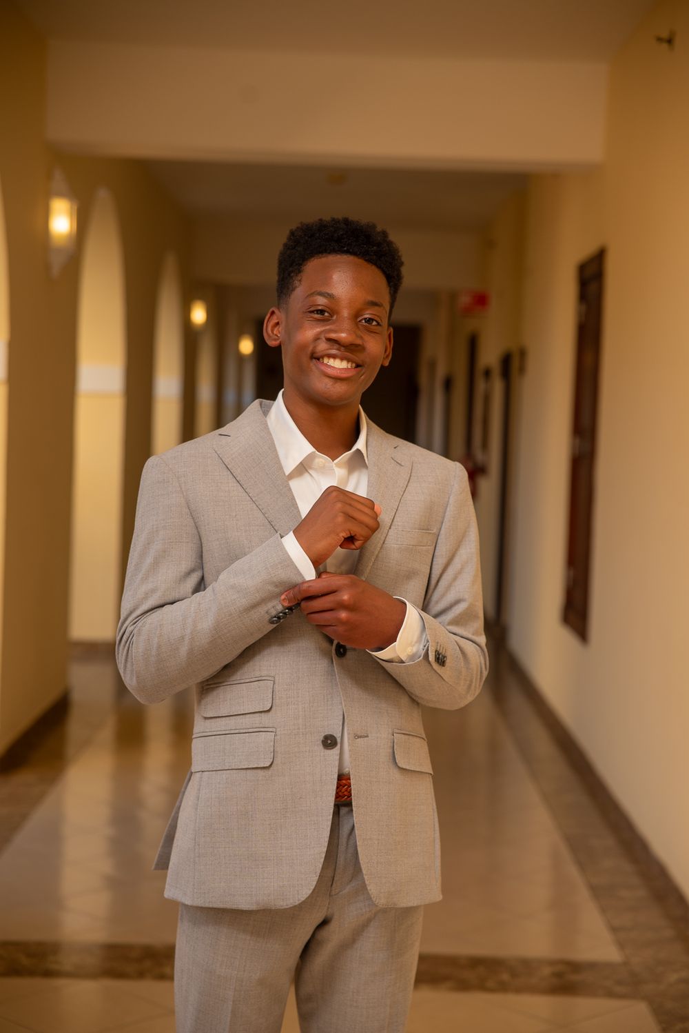 A person in a light gray suit stands in a hallway showing joyful expressions in a series of connected photos.