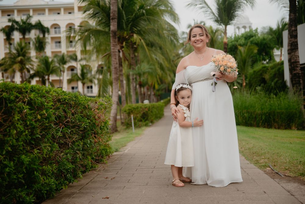 A wedding party walks along a palm tree-lined path at a tropical resort venue on a sunny day.
