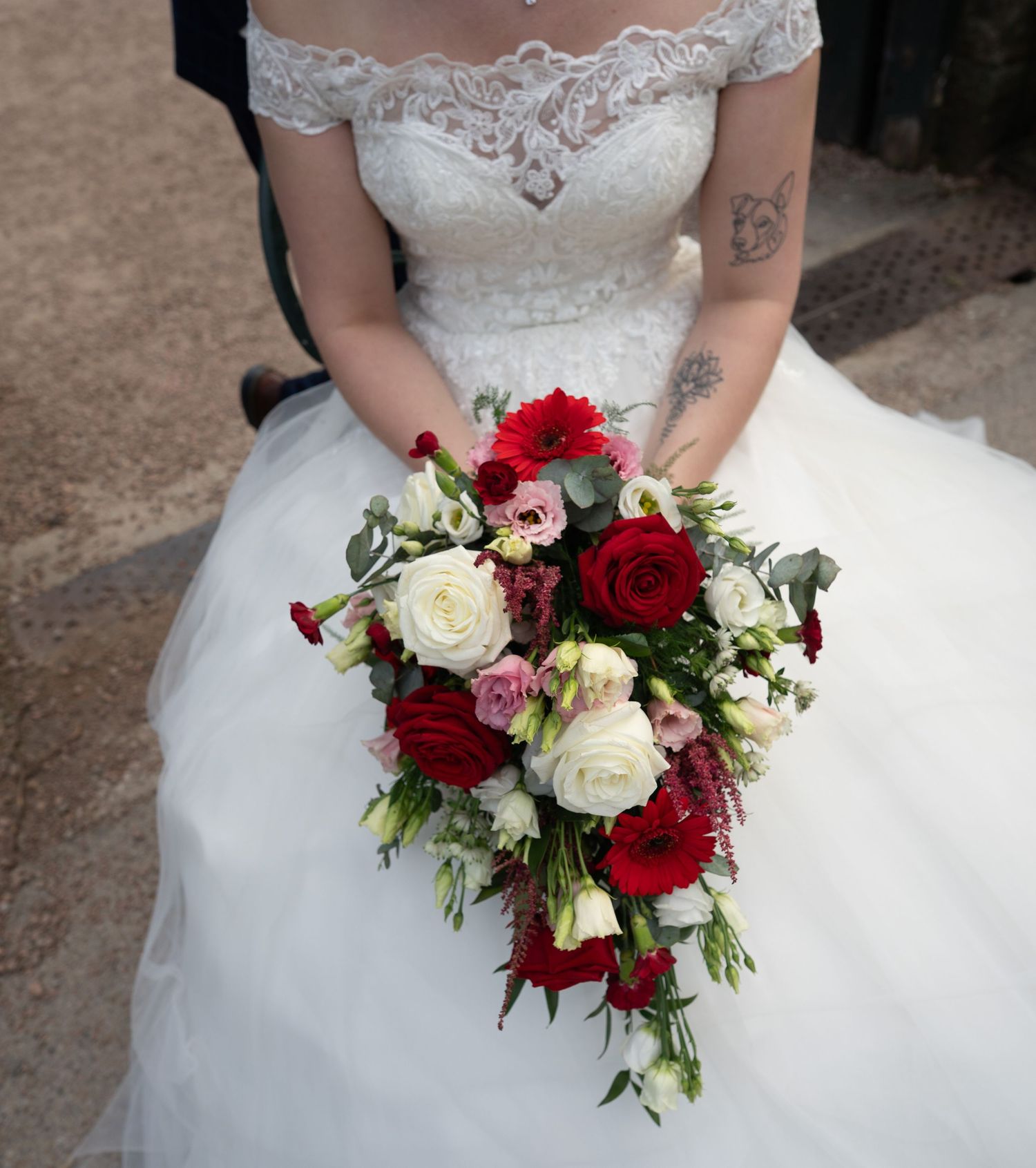Bridal bouquet featuring deep red roses and white flowers with delicate greenery.