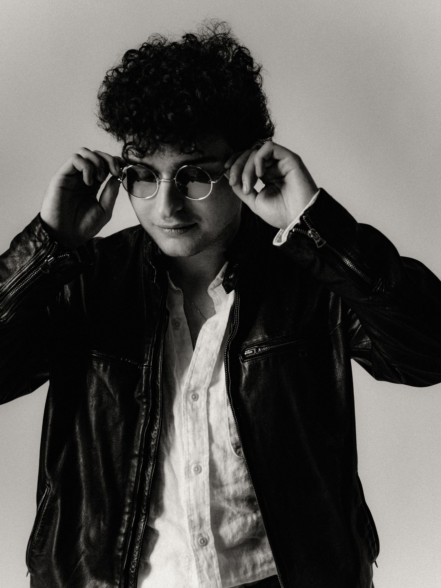 Black and white artistic portrait series showing same person in leather jacket and white shirt against neutral background.
