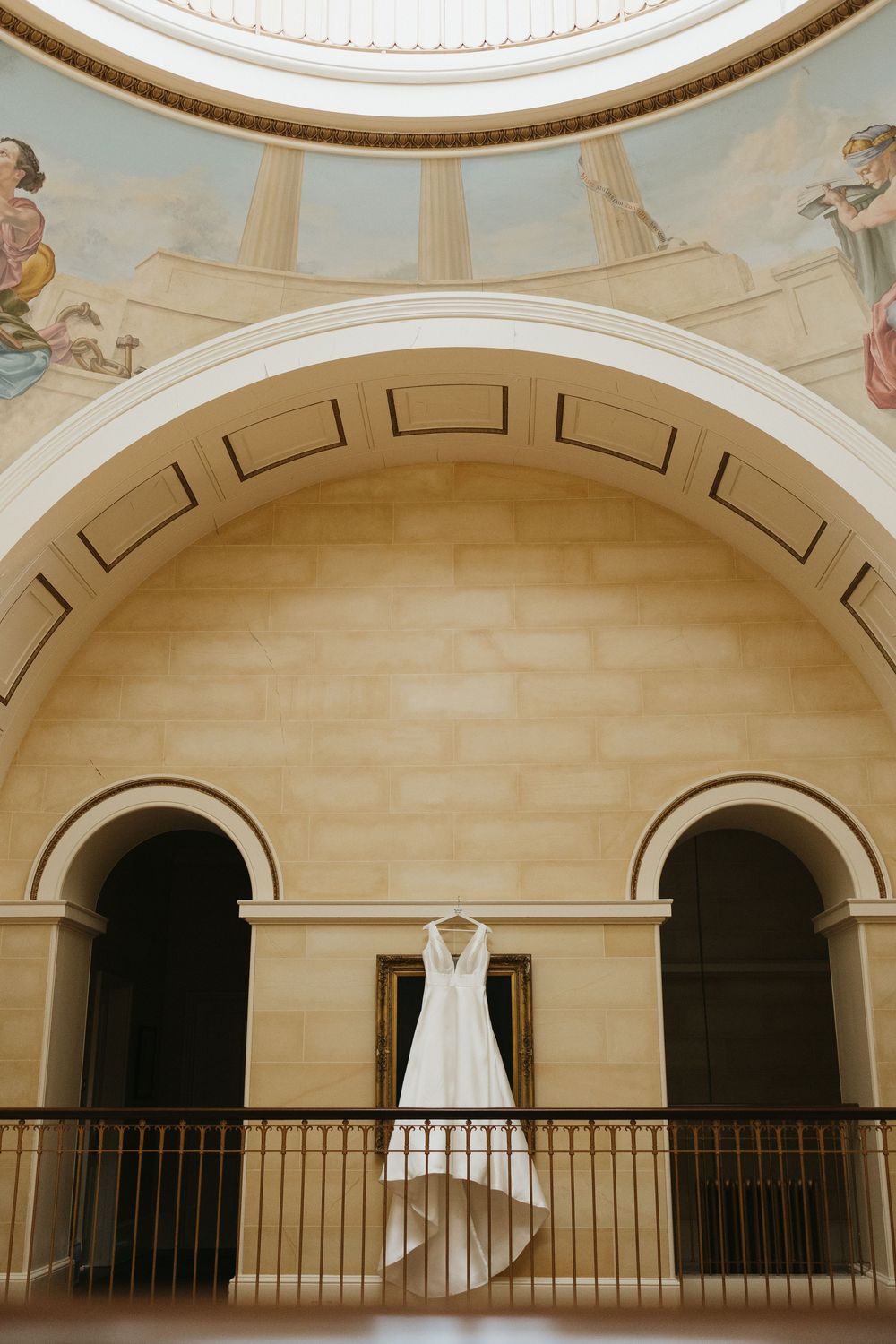 Architectural detail of arched colonnade with ornate moldings and railings in a classical building interior.